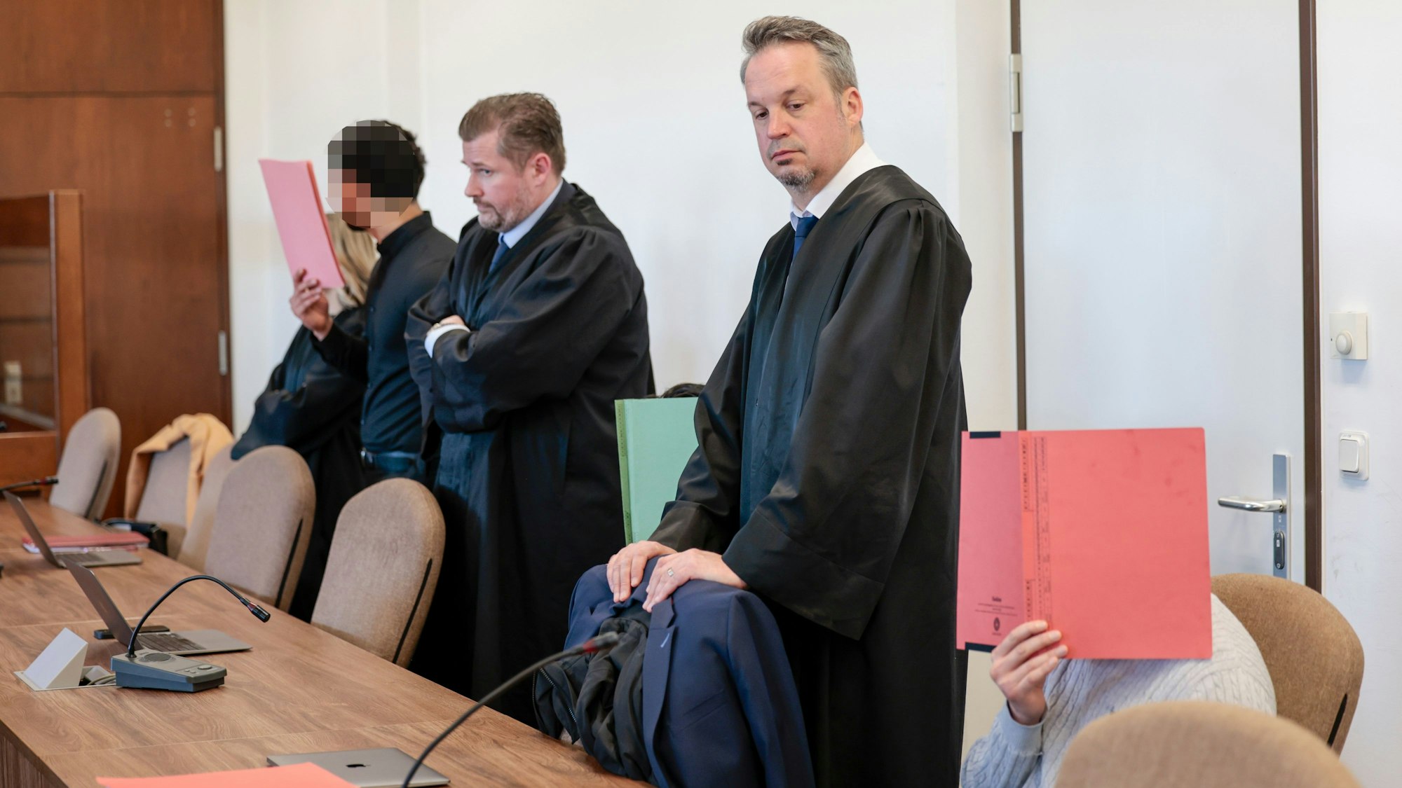 Die drei Angeklagten mit ihren Anwälten beim Prozessauftakt.