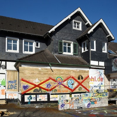 Ein altes Haus mit Bretterverschlägen, die bunt besprüht wurden.