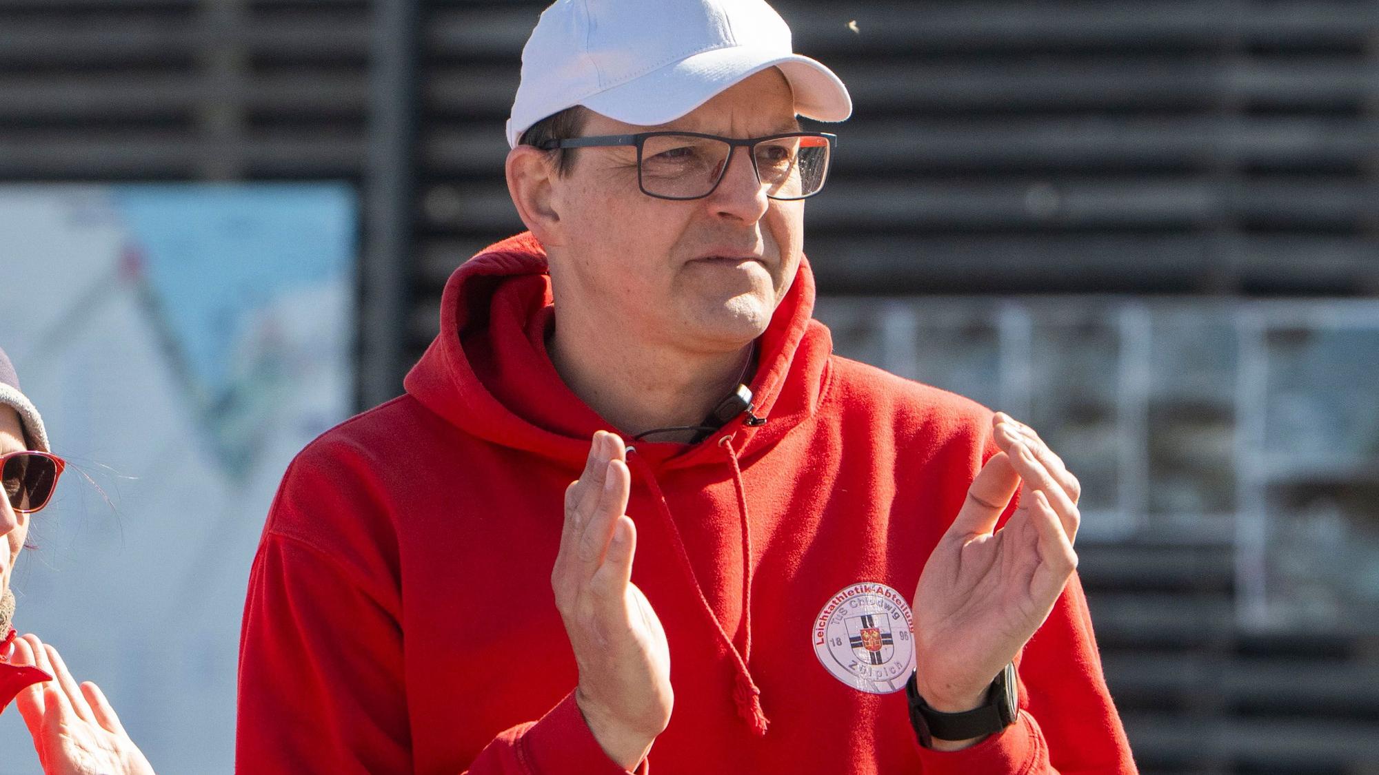 Markus Mollek vom TuS Zülpich trägt einen roten Pullover und eine weiße Kappe. Er applaudiert.