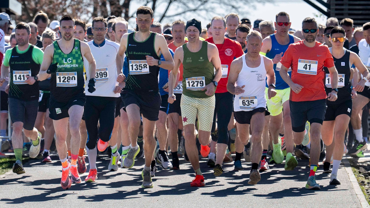 Die Teilnehmer des Chlodwiglaufs starten in Zülpich. Sie haben Zettel mit ihren Startnummern an der Kleidung befestigt.