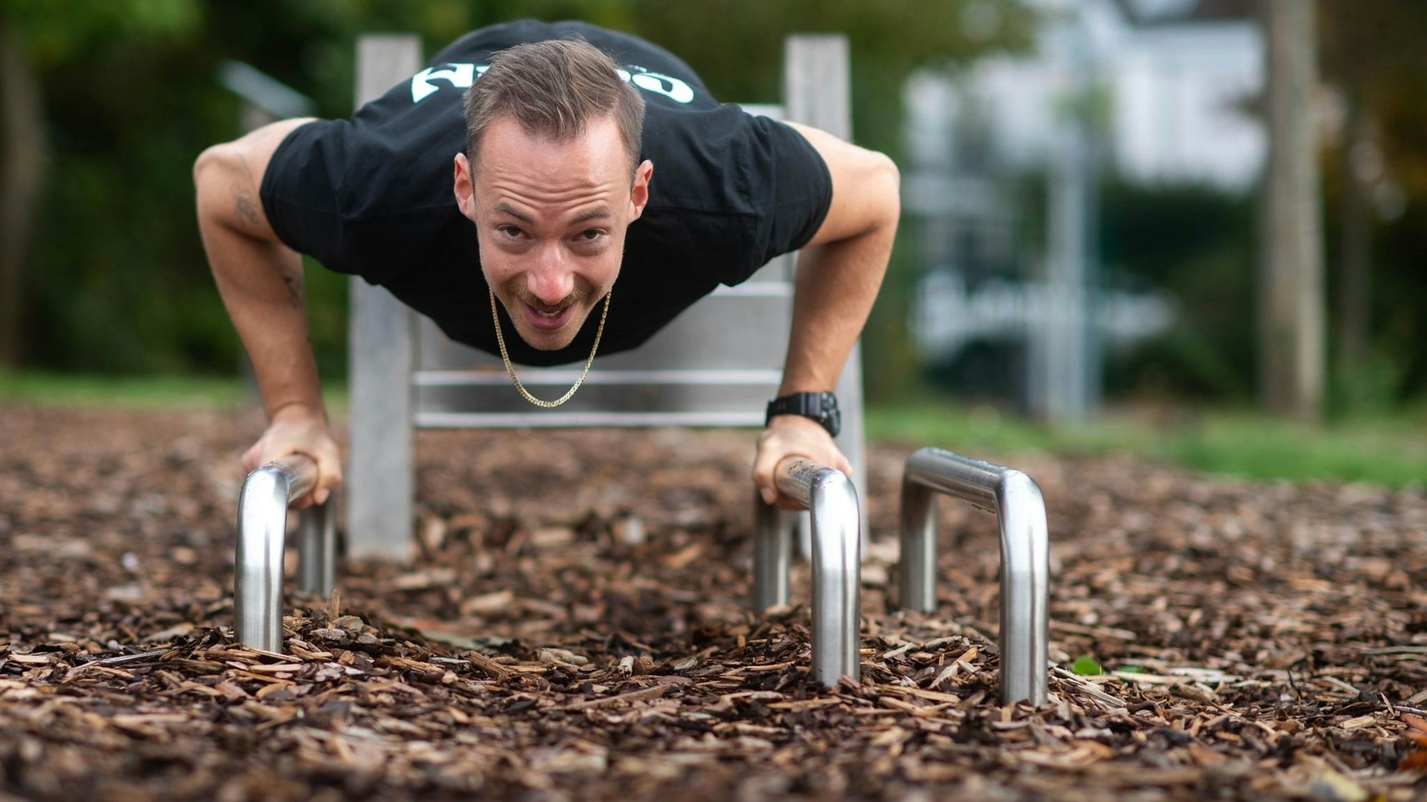 Ein Mann trainiert an einem Fitnessgerät in einem Park.
