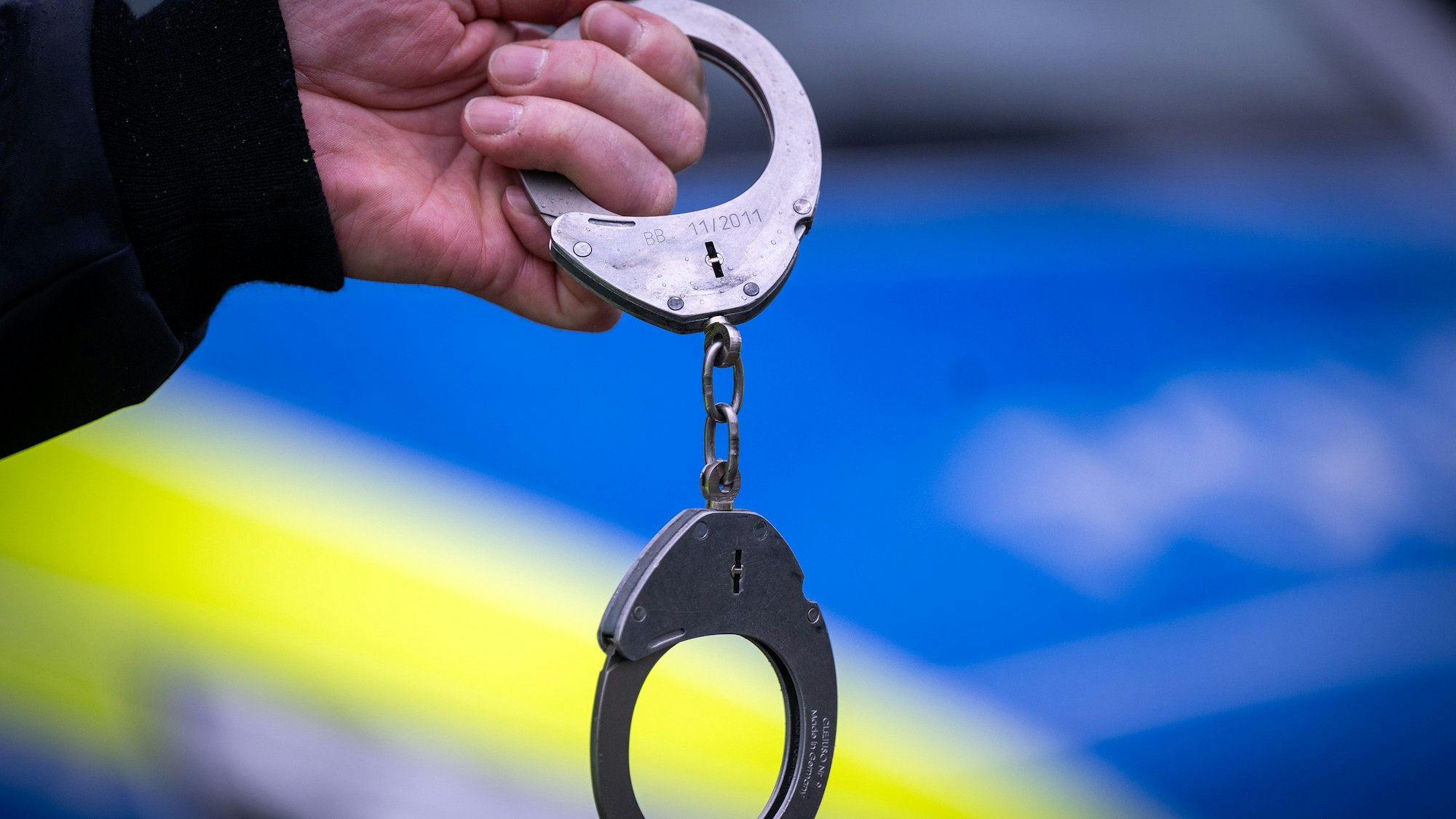 Ein Polizist hält ein Paar Handschellen. (Symbolbild)
