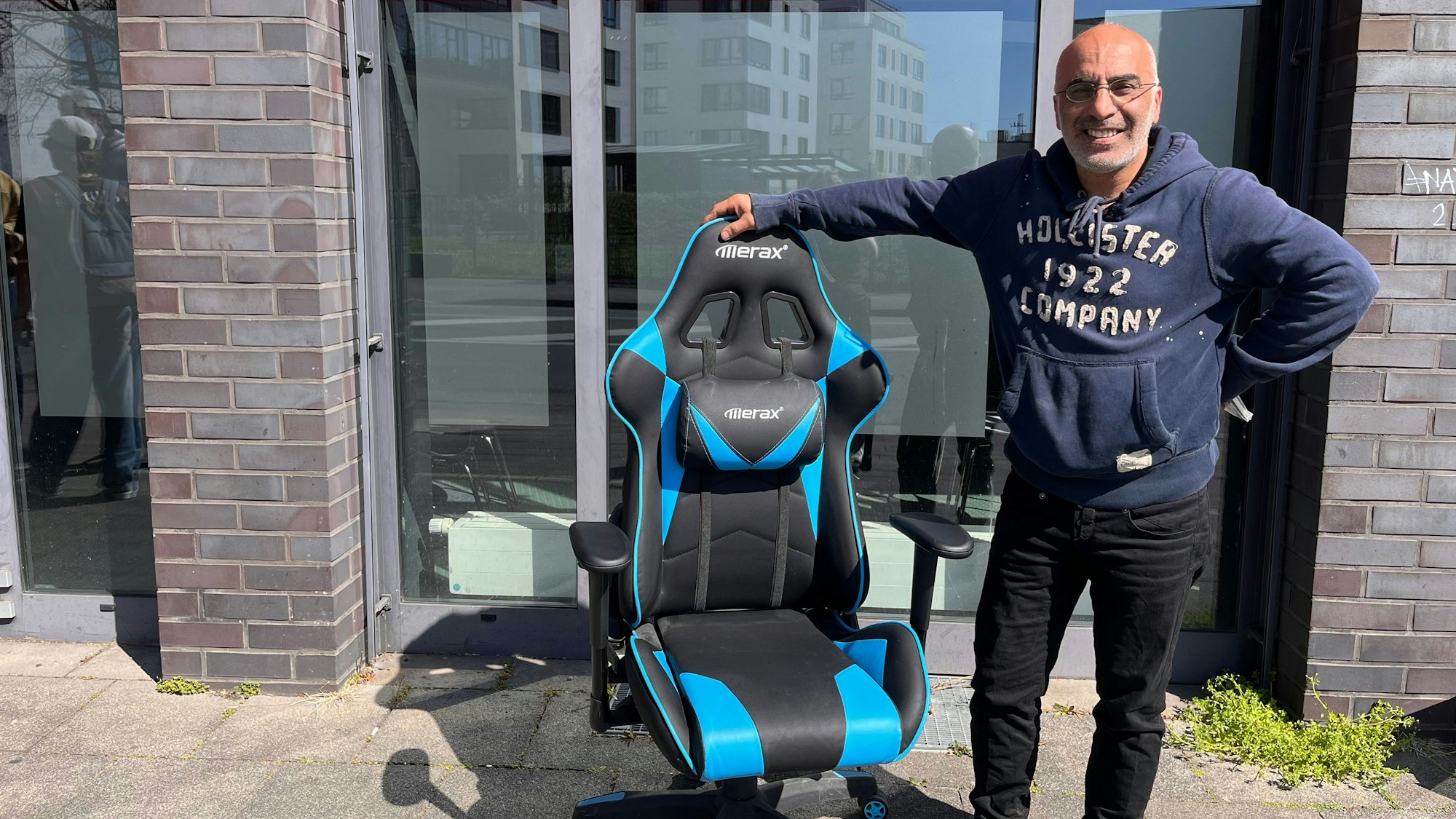 Ein Besucher der Versteigerung steht neben seinem neu erworbenen Gamer-Stuhl.