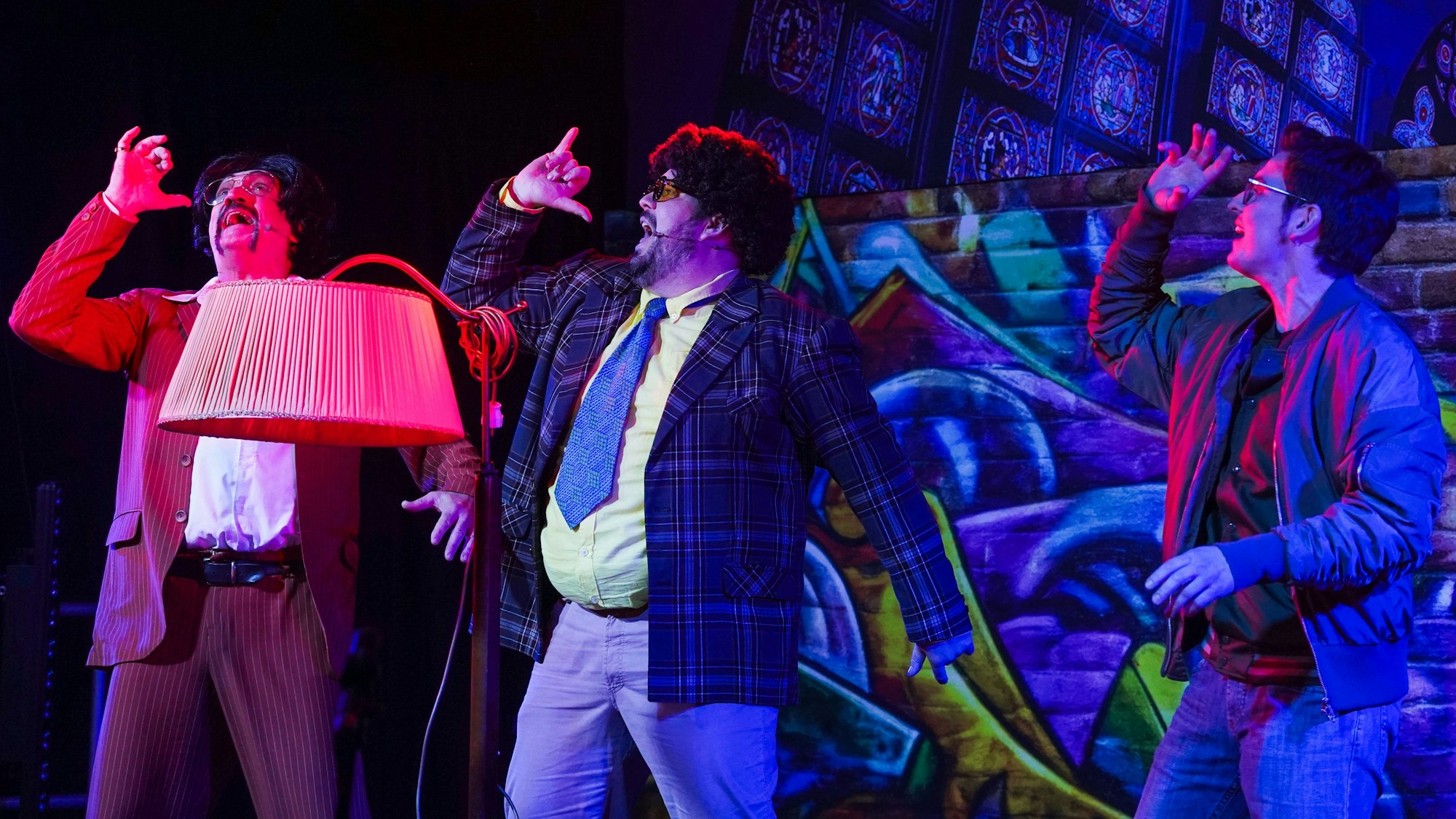 Drei Männer sind als Gangster mit Klamotten aus den 70ern Jahren verkleidet.