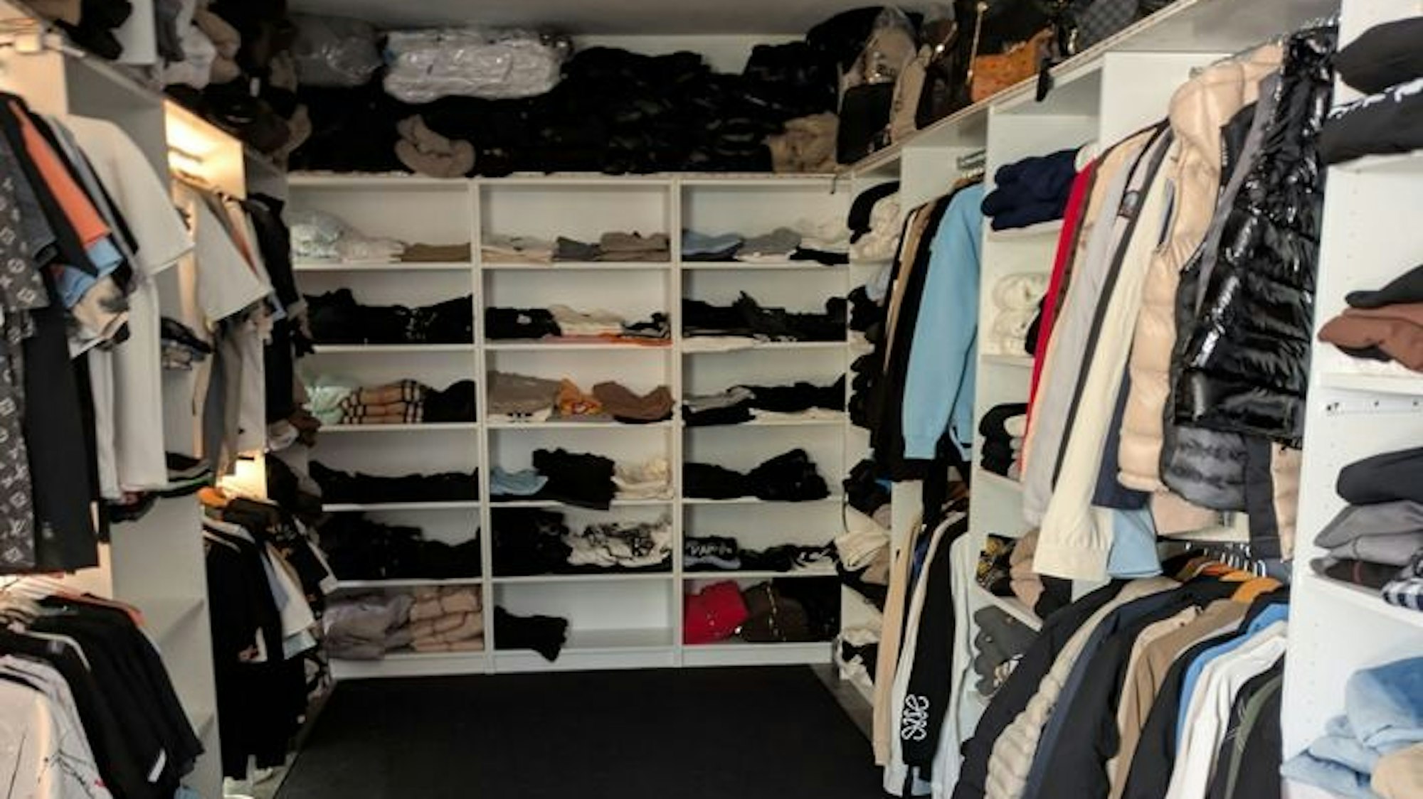 In einem Ankleidezimmer stehen Regale voller Kleidungsstücke.