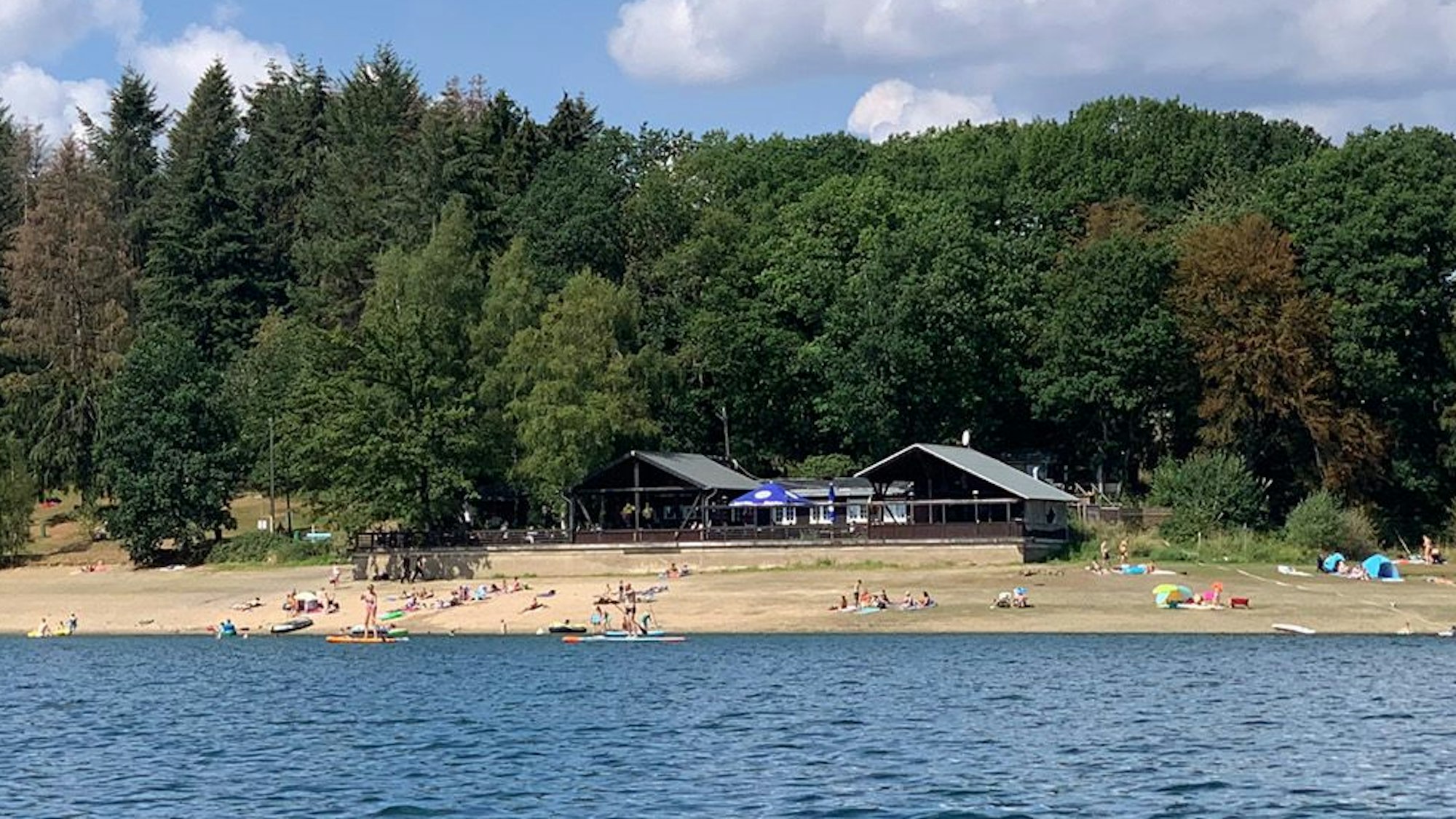 Das Foto zeigt eine Badestelle an der Bevertalsperre mit der „Zornigen Ameise“ im Hintergrund.