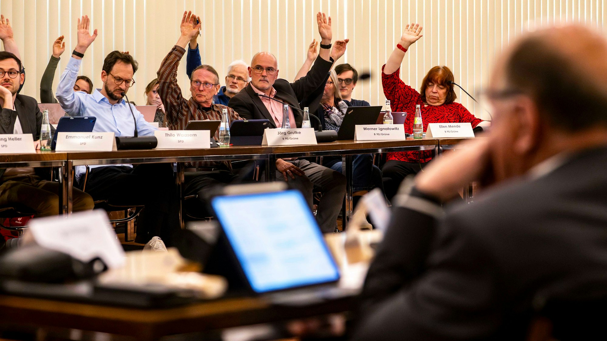 Das Bild zeigt einen Moment der Kreistagssitzung. Einige Politiker heben während der Abstimmung ihren Arm.