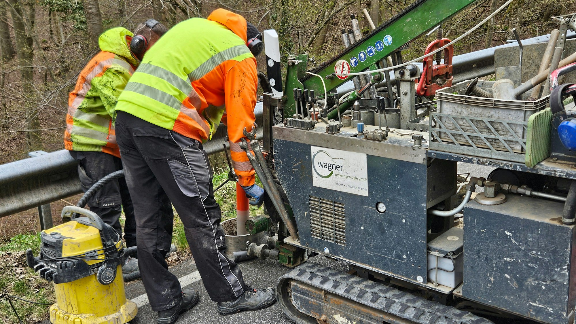 Zwei Mitarbeiter bedienen eine mobile Bohrmaschine für Straßen.
