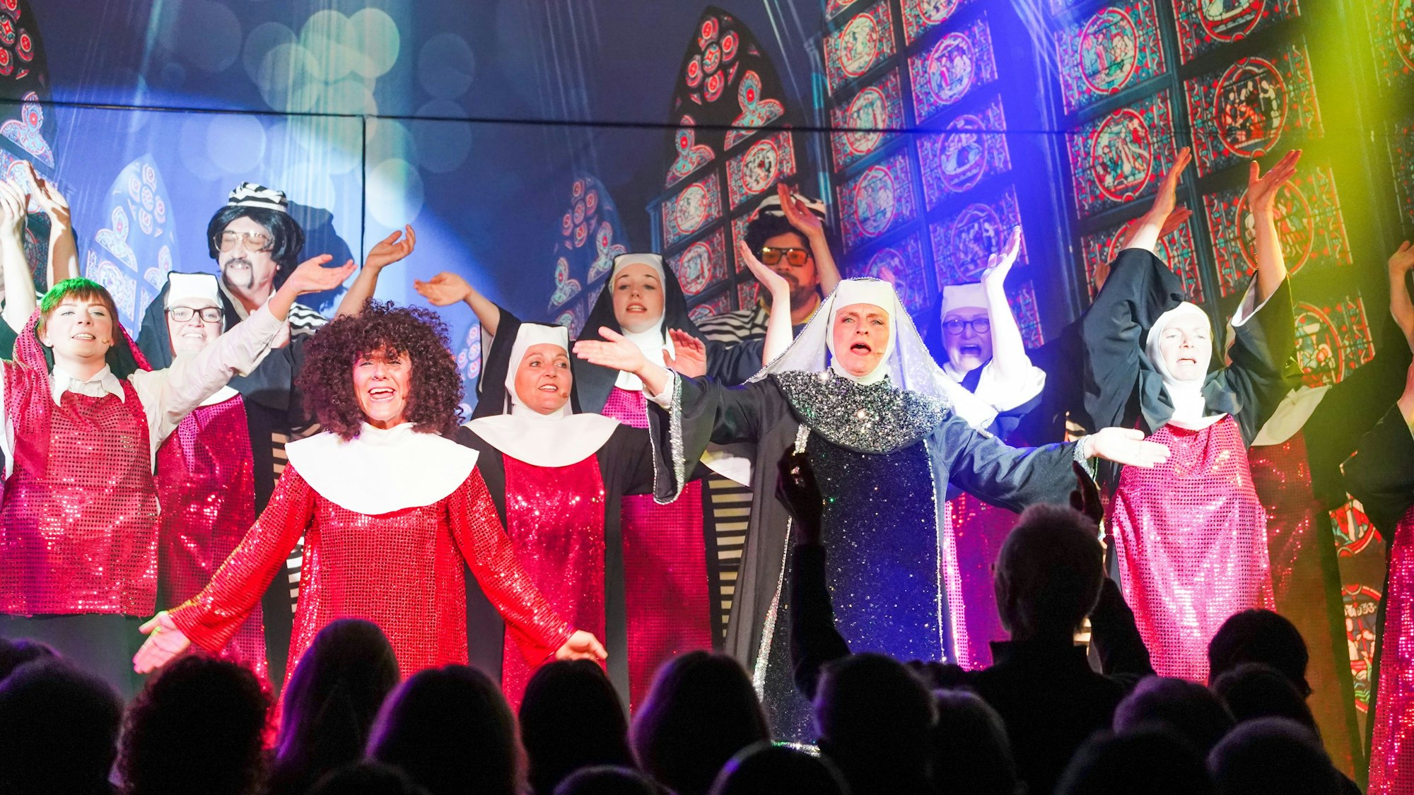 Als Nonnen verkleidete Personen singen auf einer Bühne.