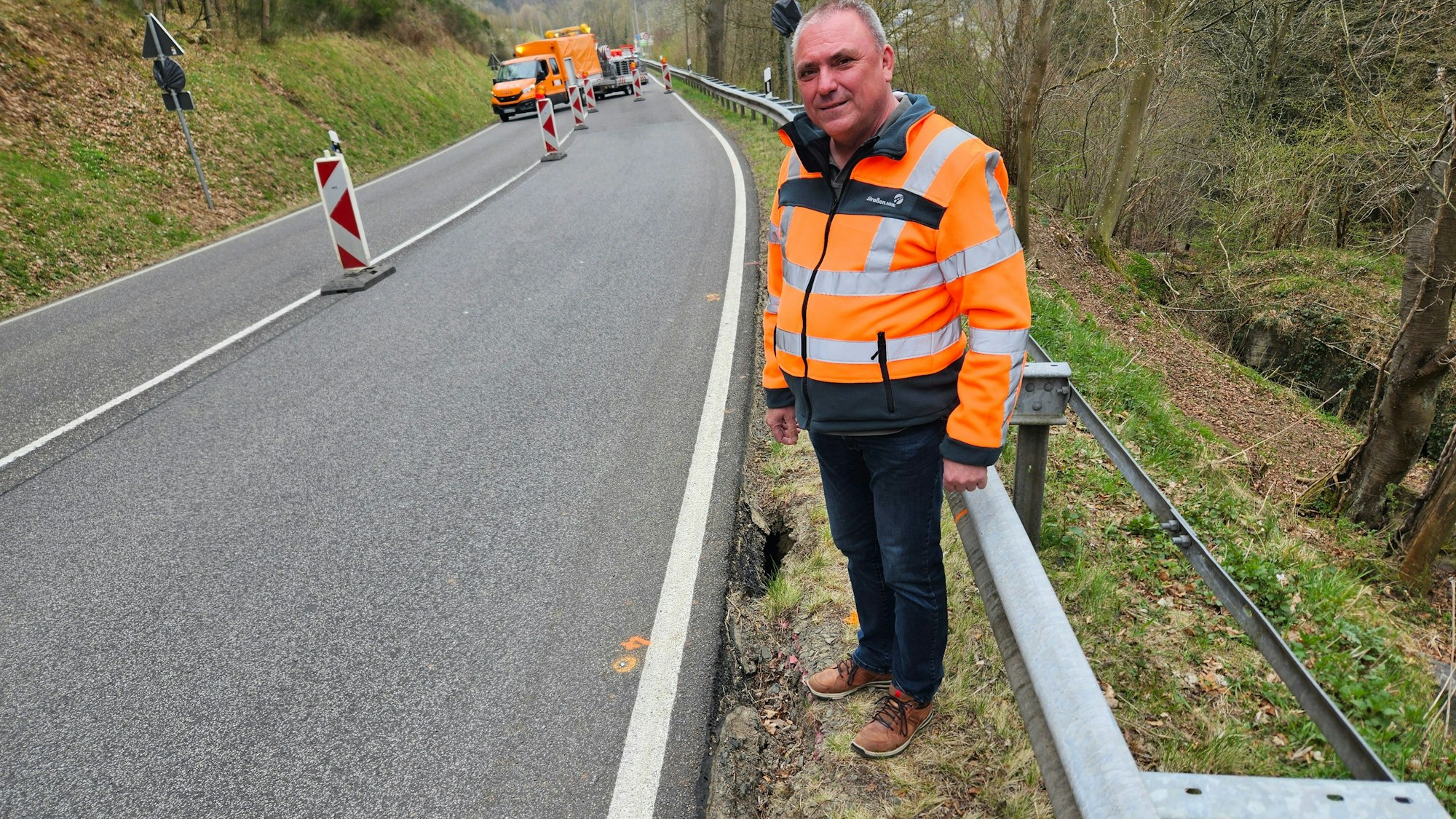 Andreas Thelen steht auf der Böschung neben dem Straßenrand. Unten sind Löcher zu sehen.