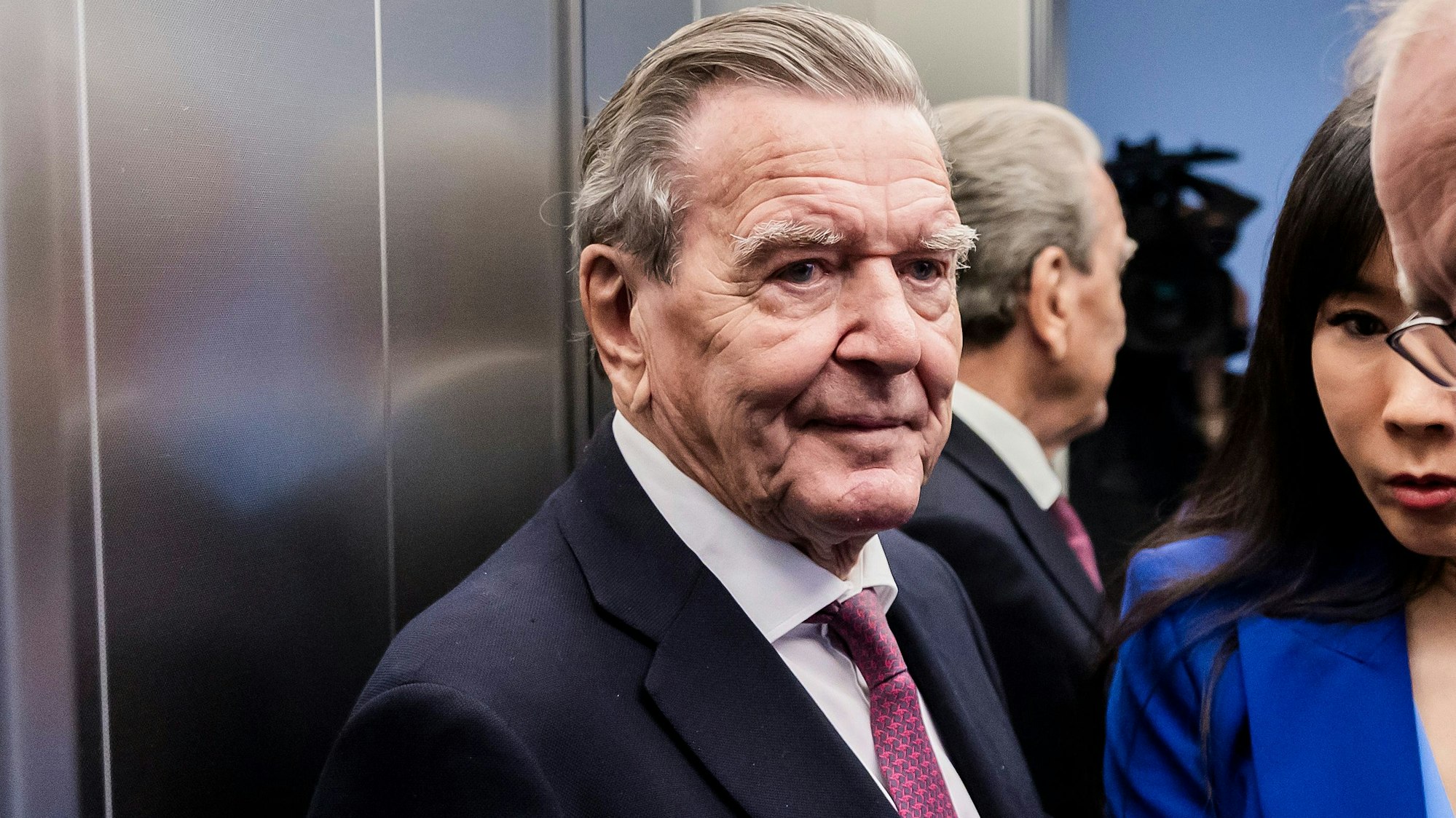 Altkanzler Gerhard Schröder (SPD, l), und seine Ehefrau Soyeon Schröder-Kim (M) stehen im Oberverwaltungsgericht (OVG) Berlin-Brandenburg nach der mündlichen Verhandlung im Prozess um den Verlust seines Büros im Bundestag in einem Aufzug.