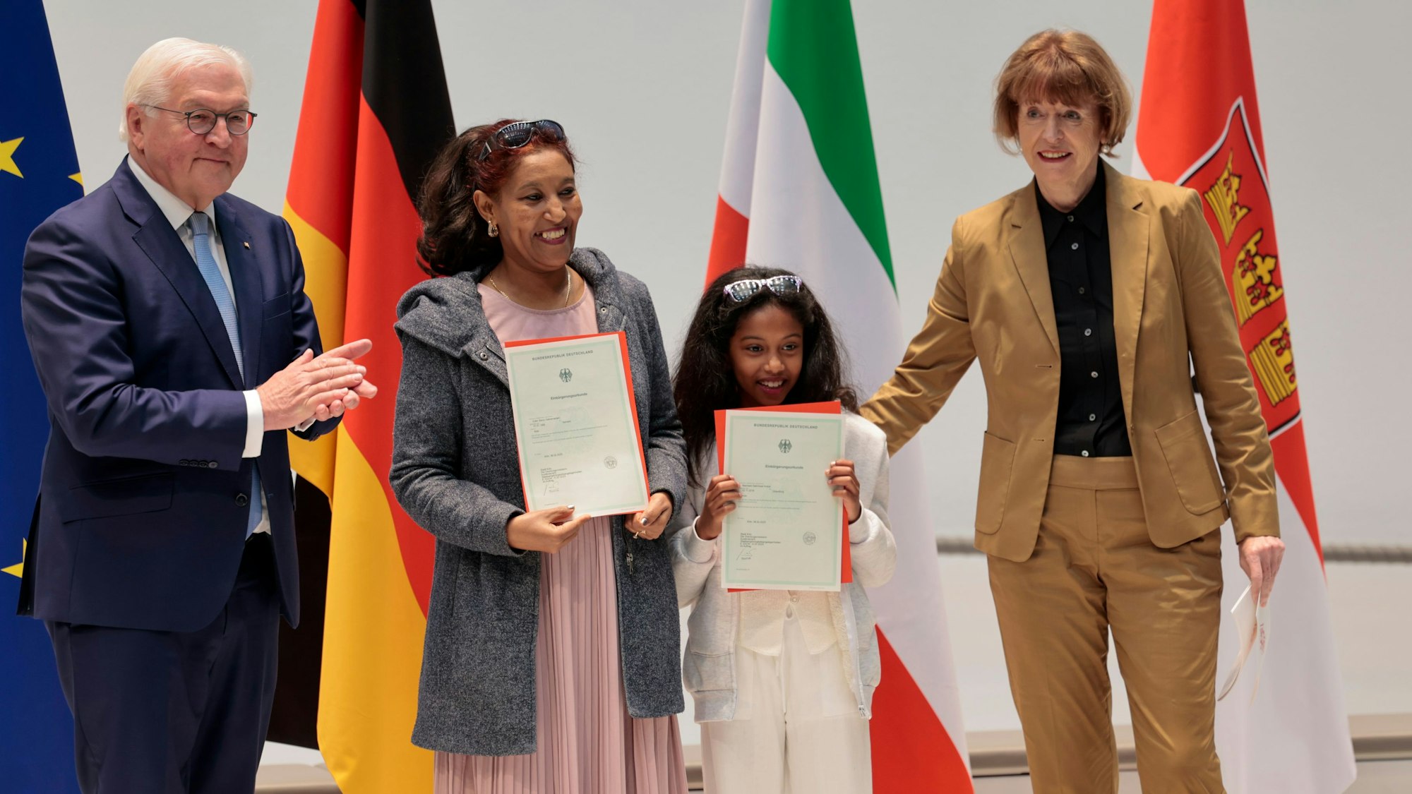 Glücklich zeigen Eden Gebremariam und ihre Tochter Nazrawit ihre Urkunden, Bundespräsident und OB freuen sich mit.