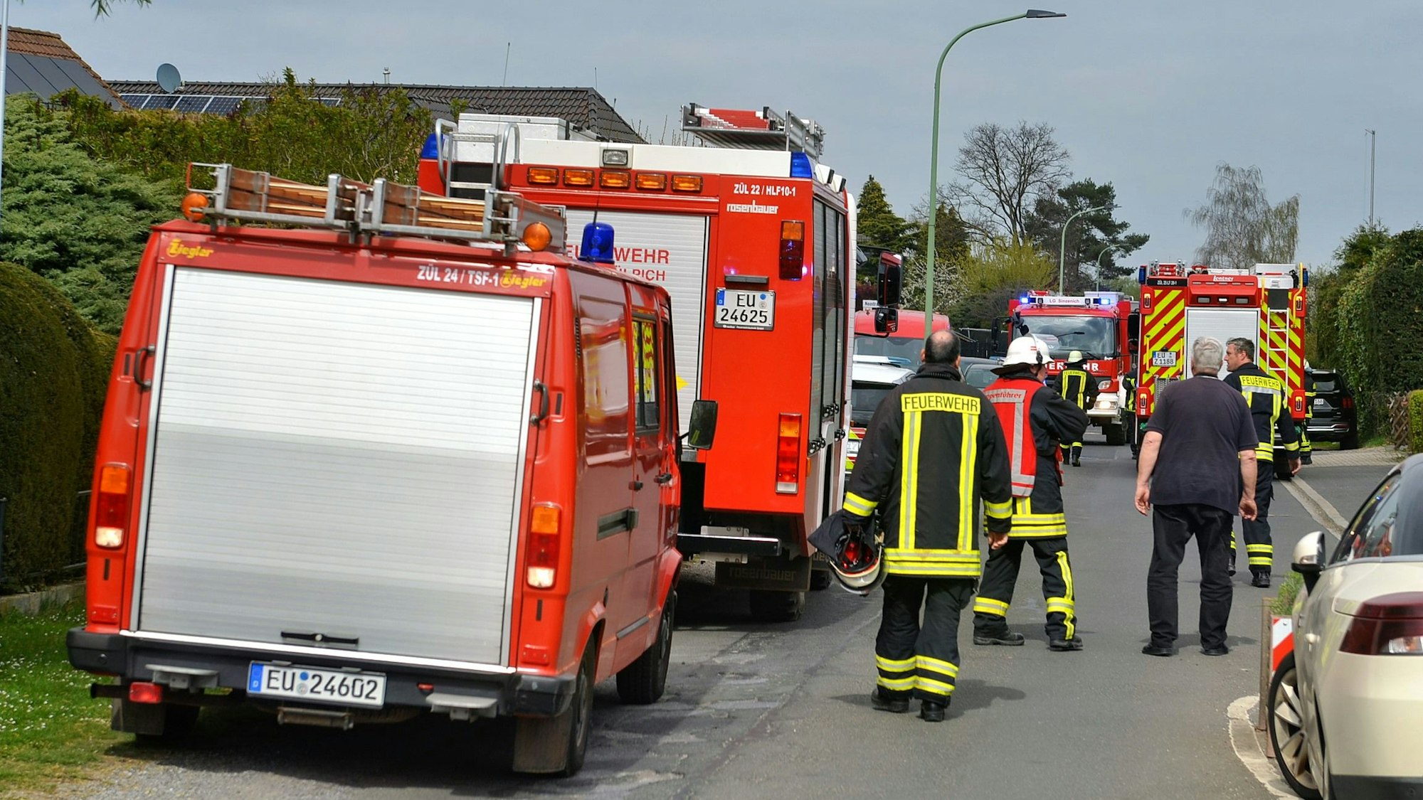 Feuerwehrmänner stehen neben Löschfahrzeugen auf der Straße.