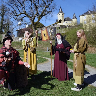 Mittelalterlich gekleidete Akteure vor dem Schloss.