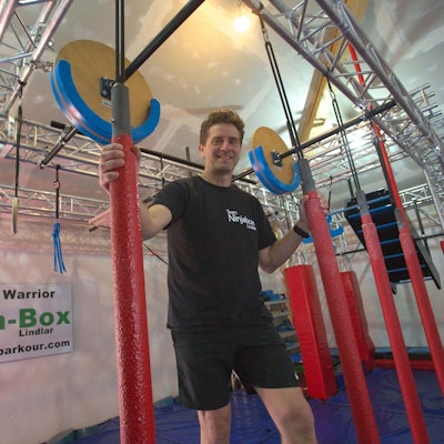 Blick auf einen Mann, der nach an der Decke befestigten Stangen fasst.