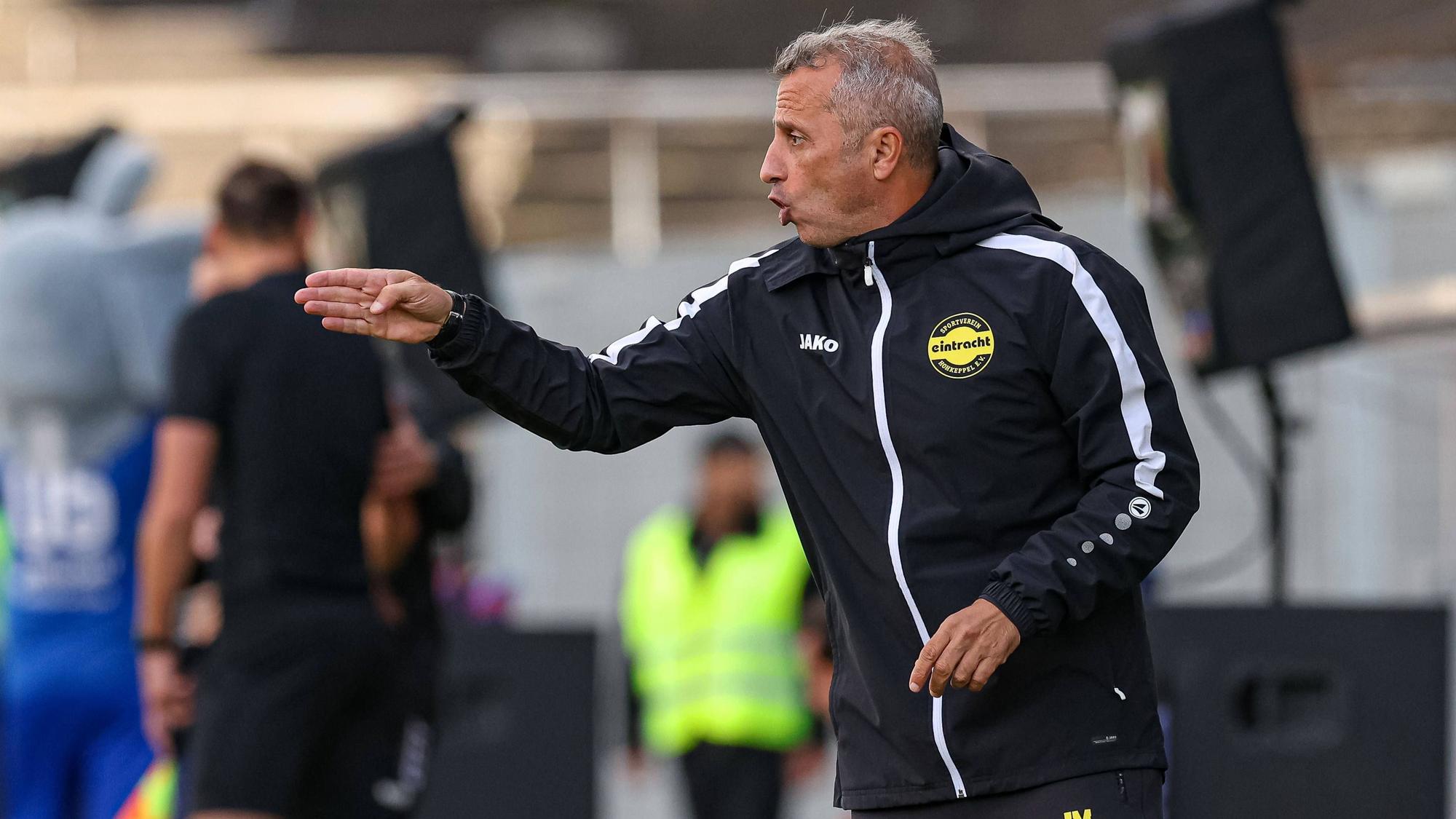 Ein Fußballtrainer gestikuliert am Spielfeldrand.