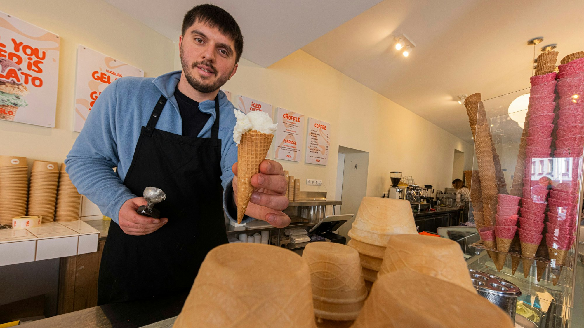 Ein Mitarbeiter zeigt ein Eis im Hörnchen.