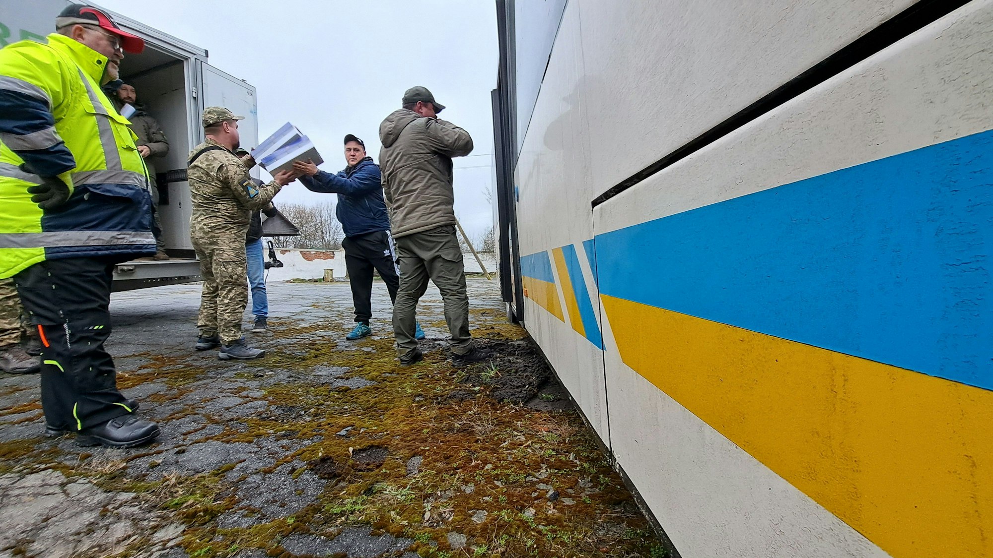 Männer entladen einen Bus in Chemlnyzkyj/Ukraine.