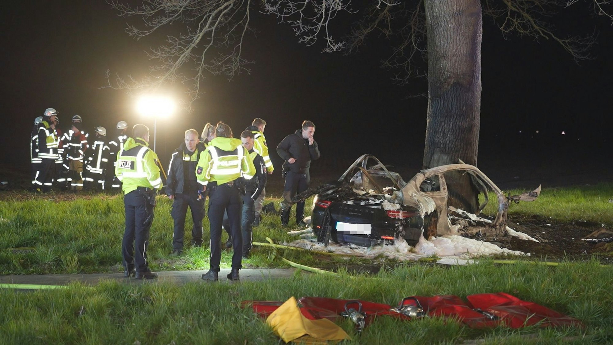 Einsatzkräfte stehen an einer Unfallstelle. Zwei 17-Jährige sind in der Nacht in Syke in Niedersachsen mit einem Sportwagen gegen einen Baum geprallt und im Wagen verbrannt.