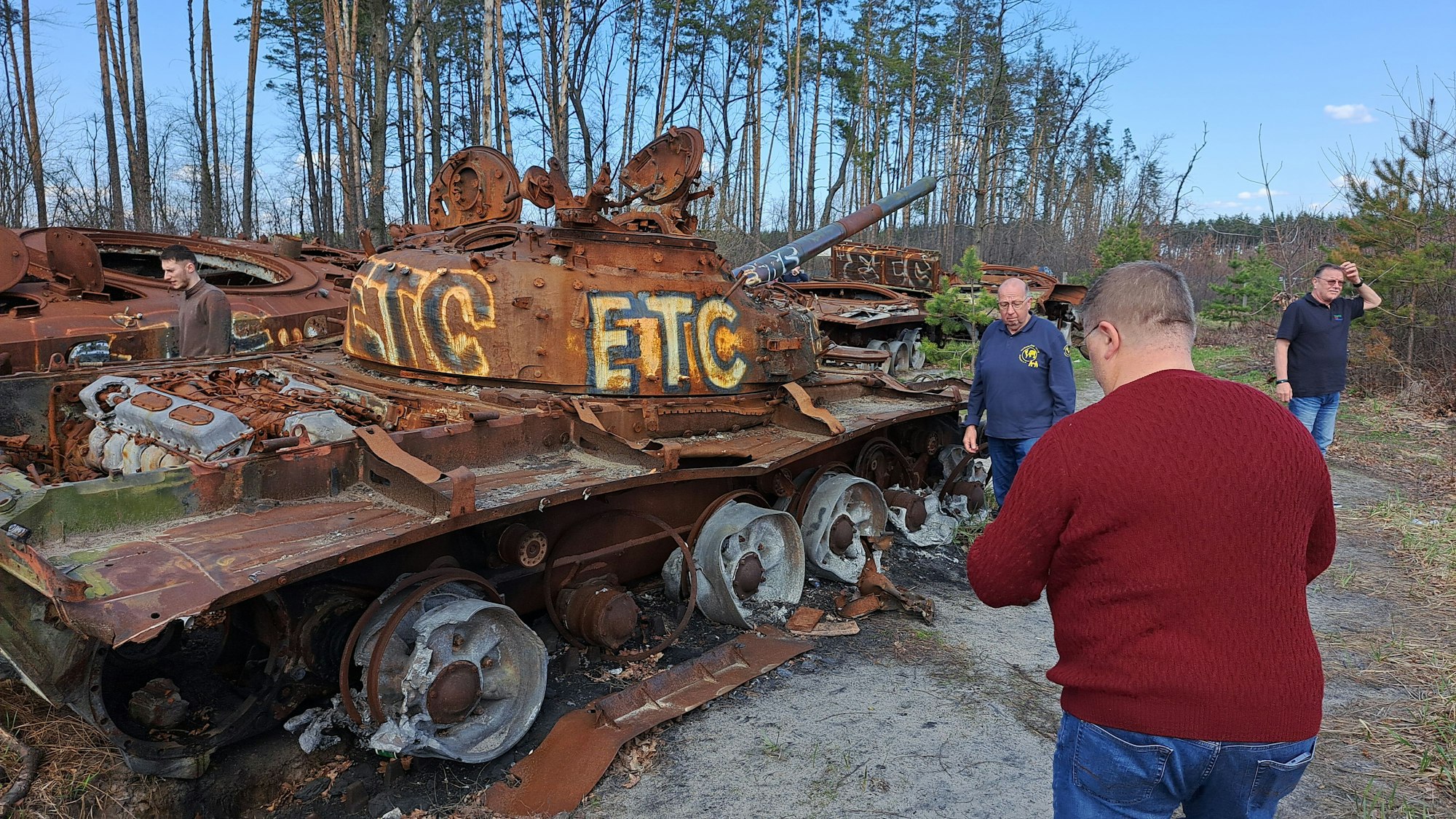 Hilfstransporteure aus de Bergischen schauen sich die 2022 beim Angriff auf Kiew gestoppten und ausgebrannten russischen Panzer bei Butscha an.