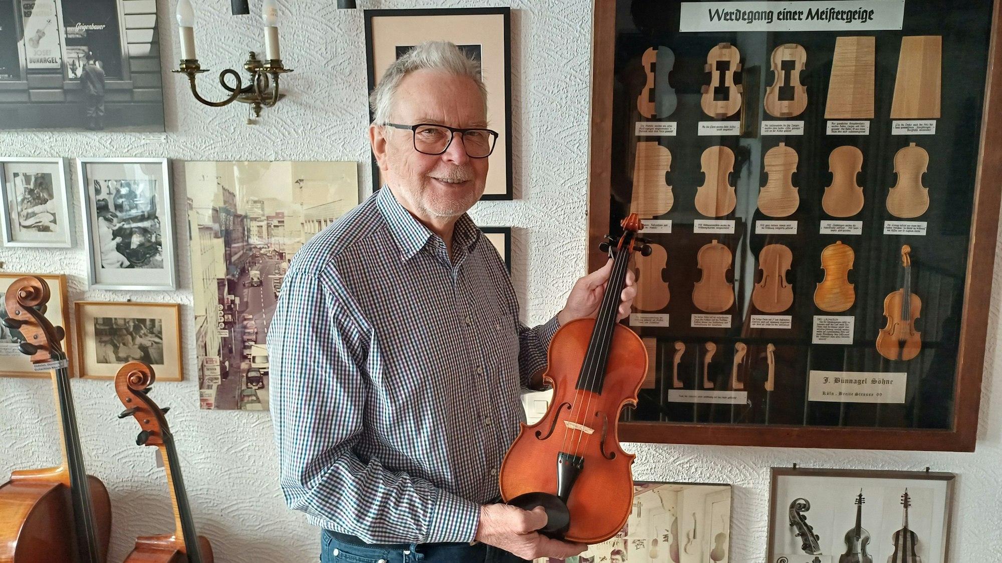 Lange Geschichte: Heribert Bünnagel hält eine selbstgefertigte Geige in seinen Händen. Die Bilder erinnern an die Familientradition.