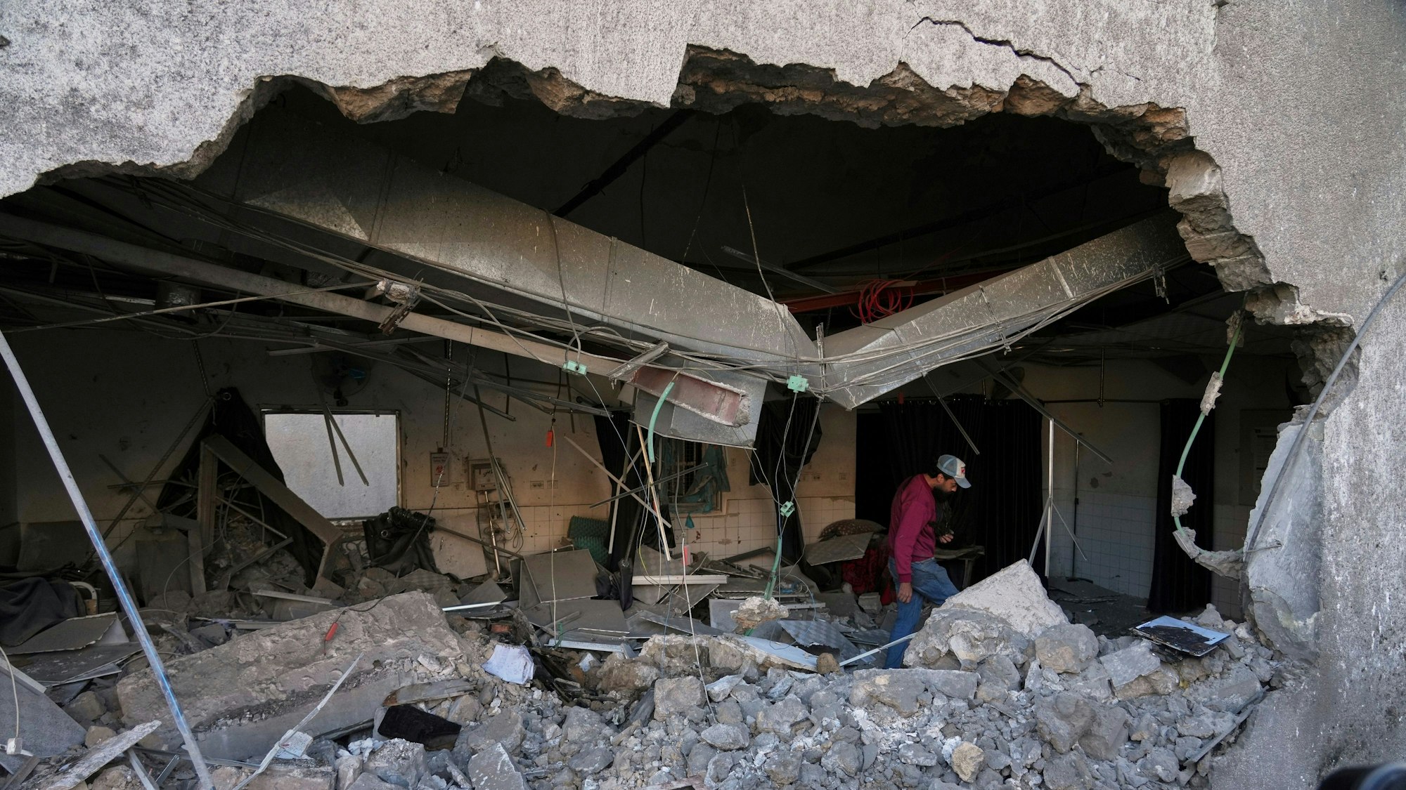 Ein meterhohes Loch klafft in einer Betonmauer. Im Hintergrund sind Fliesen und Spiegel zu sehen, vorn Trümmer.