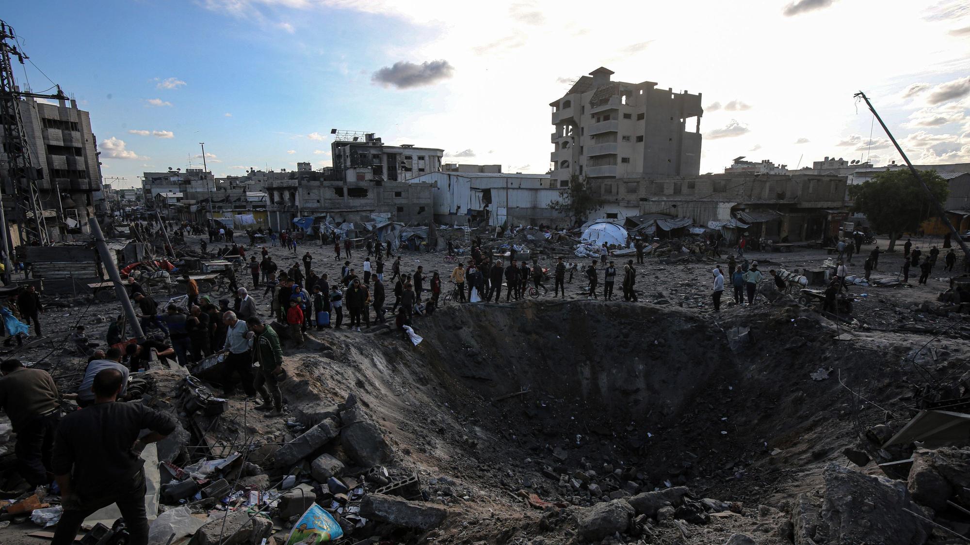 Palästinensische Gebiete, Gaza-Stadt: Palästinenser versammeln sich um einen großen Krater nach einem israelischen Angriff auf eine Metallwerkstatt im Stadtteil Zaytun in Gaza-Stadt.