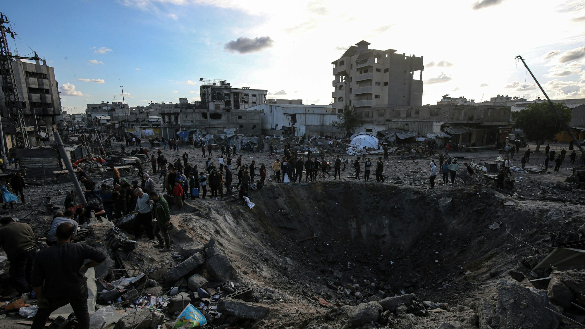 Palästinensische Gebiete, Gaza-Stadt: Palästinenser versammeln sich um einen großen Krater nach einem israelischen Angriff auf eine Metallwerkstatt im Stadtteil Zaytun in Gaza-Stadt.