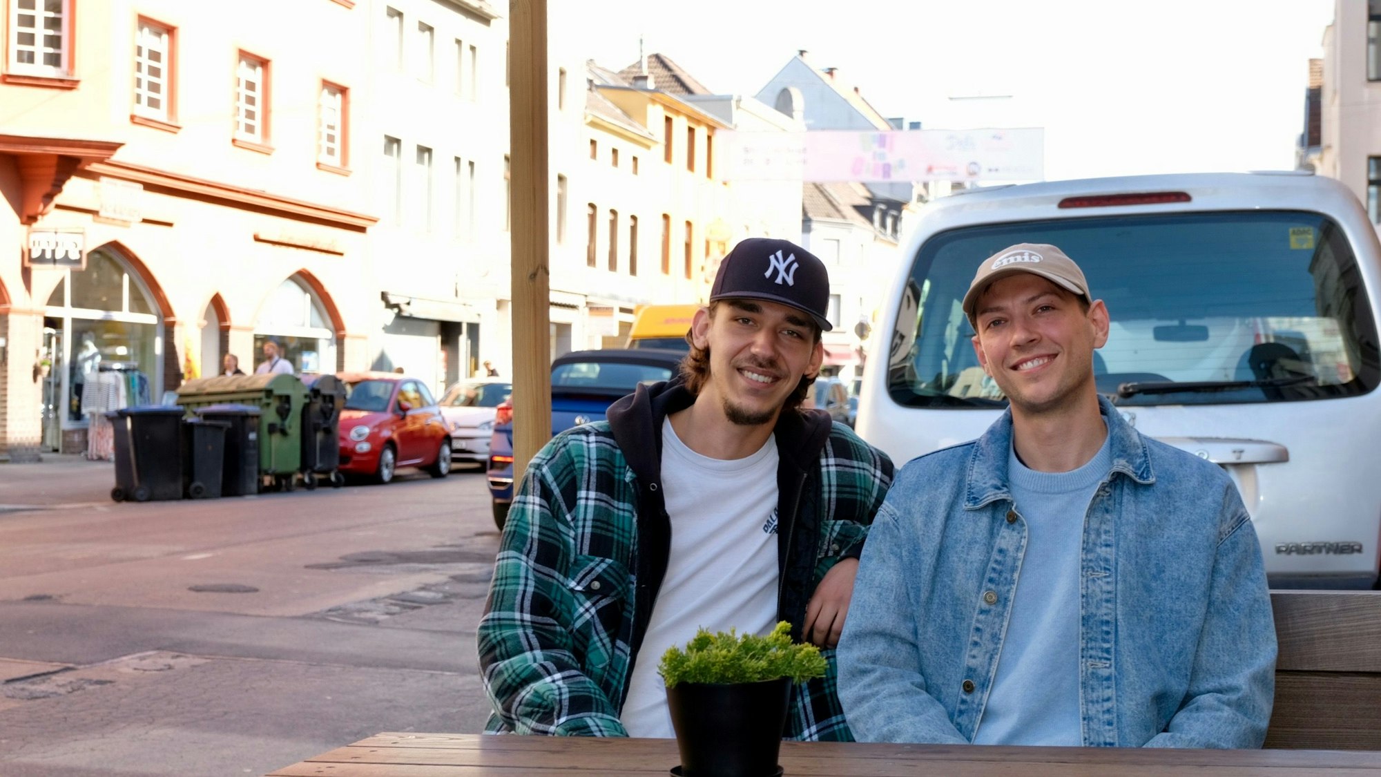 Zwei junge Männer sitzen im Außenbereich des Deli an der Berrenrather Straße.