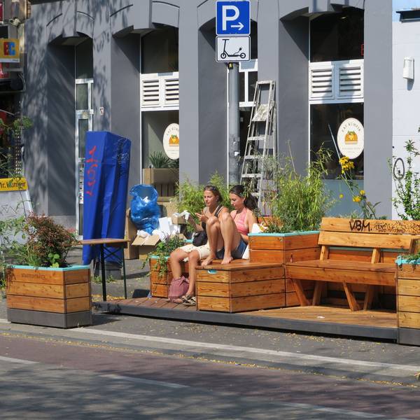 Zwei Mädchen sitzen auf Holzmöbeln an der Venloer Straße.