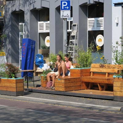 Zwei Mädchen sitzen auf Holzmöbeln an der Venloer Straße.