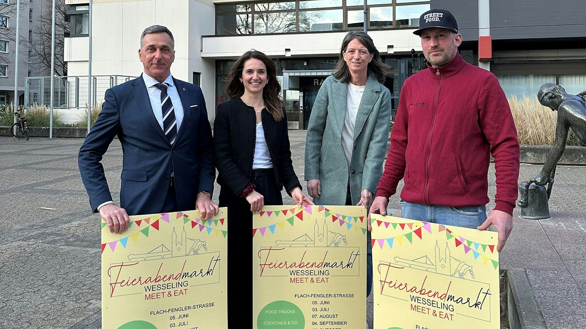 Zwei Frauen und zwei Männer halten Plakate.