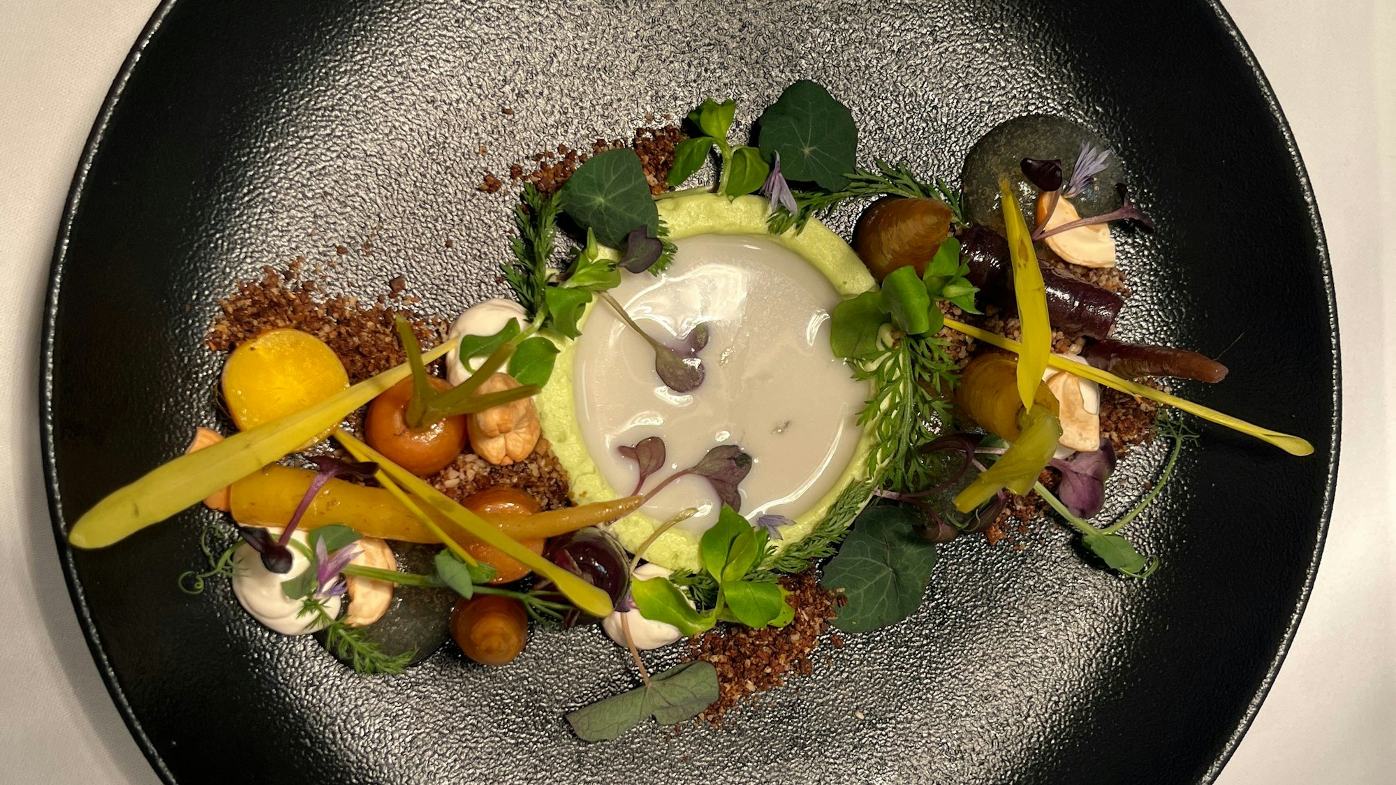 Zur Vorspeise gibt es Wildkräutersalat mit confierten Karotten und Cashewmilch.