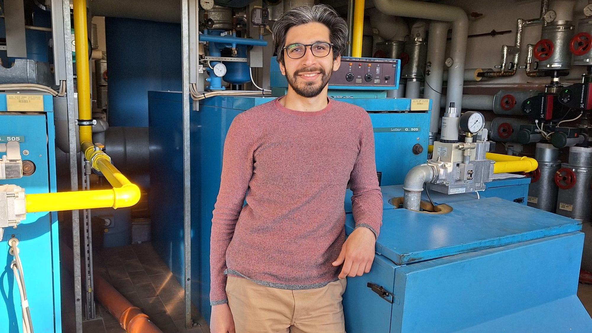 Der Energiemanager Nima Haghighatian lehnt sich mit dem Ellbogen an die Heizungsanlage der Grundschule in Dahlem.