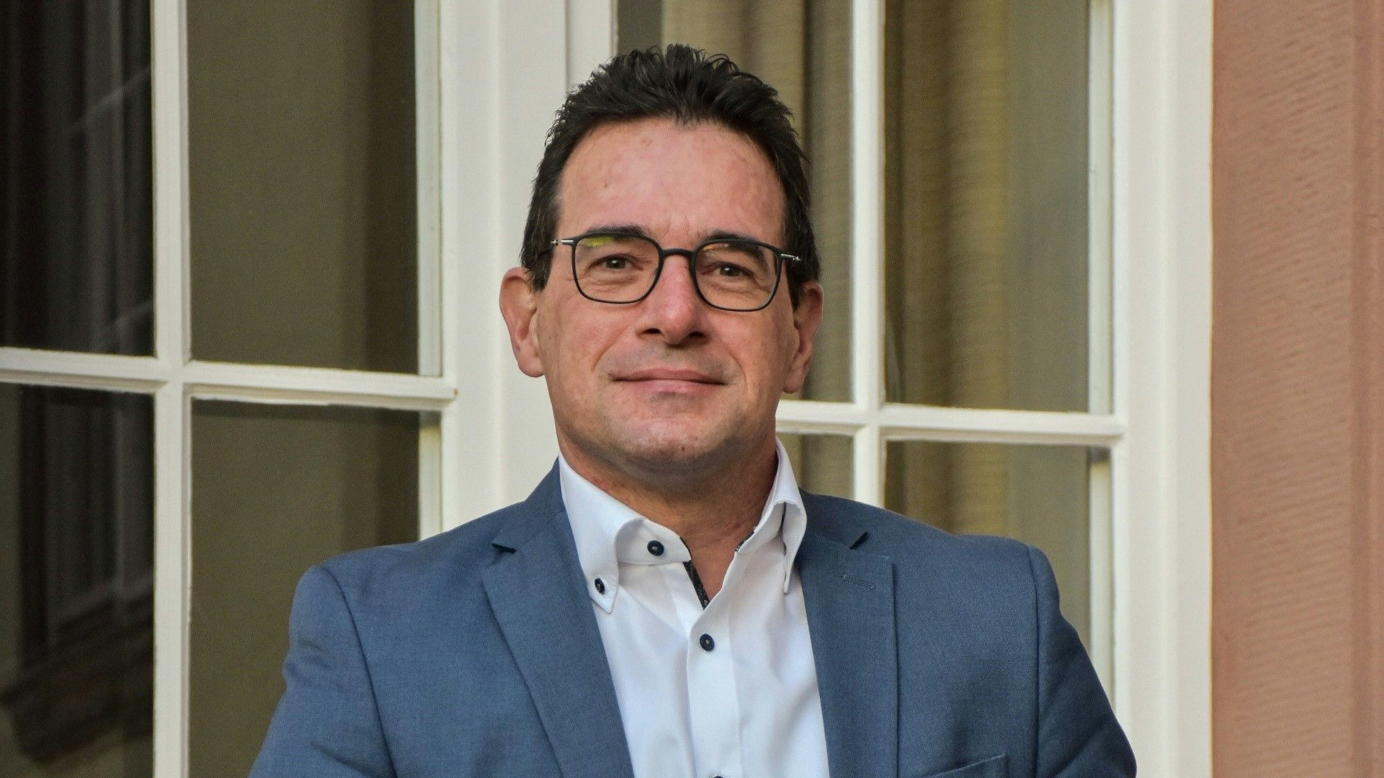 Das Foto zeigt Frank Vellen, der ein weißes Hemd unter einem blaugrauen Sakko trägt.