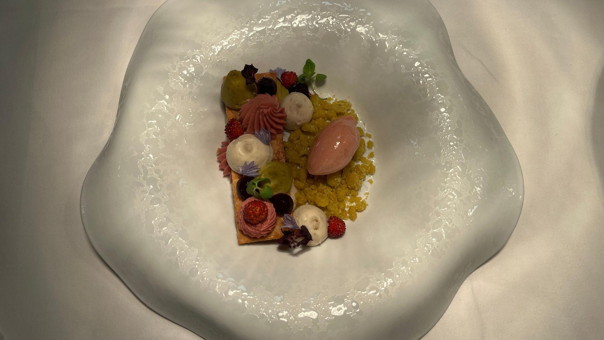 Vanillemousse, Erdbeer- und Pistazienganache werden auf karamellisiertem Blätterteig angerichtet, dazu gibt es Erdbeer-Sorbet.