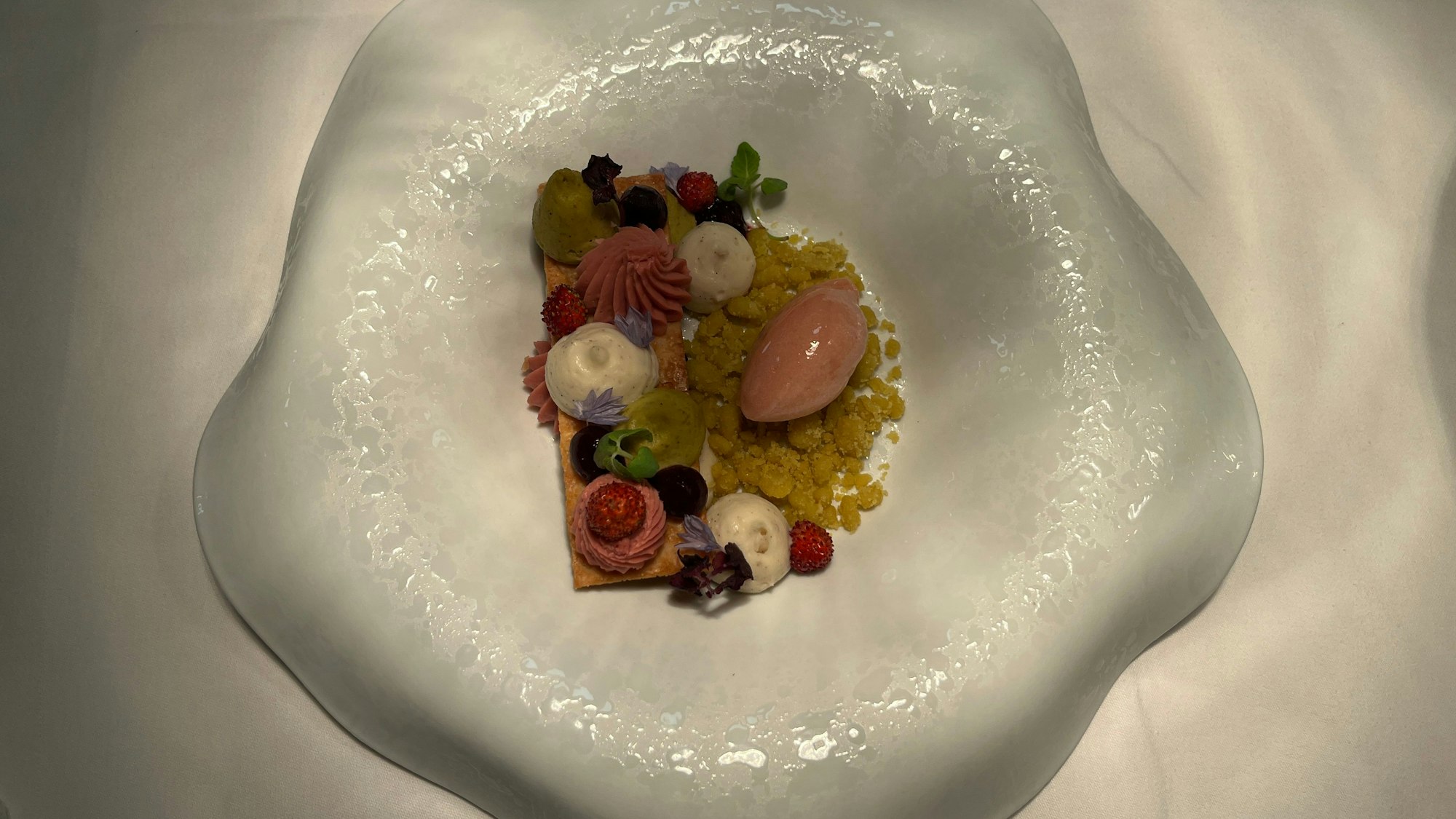 Vanillemousse, Erdbeer- und Pistazienganache werden auf karamellisiertem Blätterteig angerichtet, dazu gibt es Erdbeer-Sorbet.