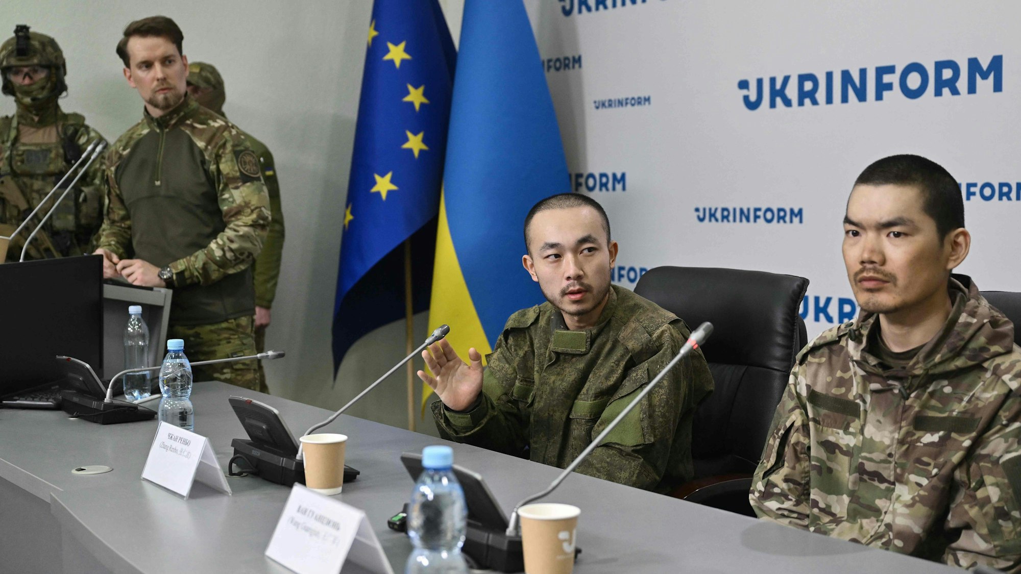 Chinese nationals Zhang Renbo (C) and Wang Guangjun (R) look on during a press conference in Kyiv on April 14, 2025, amid the Russian invasion of Ukraine. Two Chinese nationals were captured by Ukrainian forces in the Donetsk region during what they claimed to be their first combat mission on the frontline. (Photo by Genya SAVILOV / AFP)