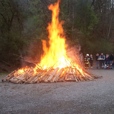 Ein Feuerwehrmann beaufsichtigt ein Osterfeuer.