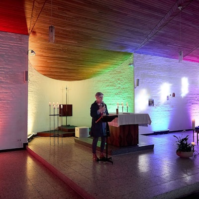 Uschi Grab steht an einem Pult in der bunt beleuchteten Kapelle in Schleiden-Scheuren.