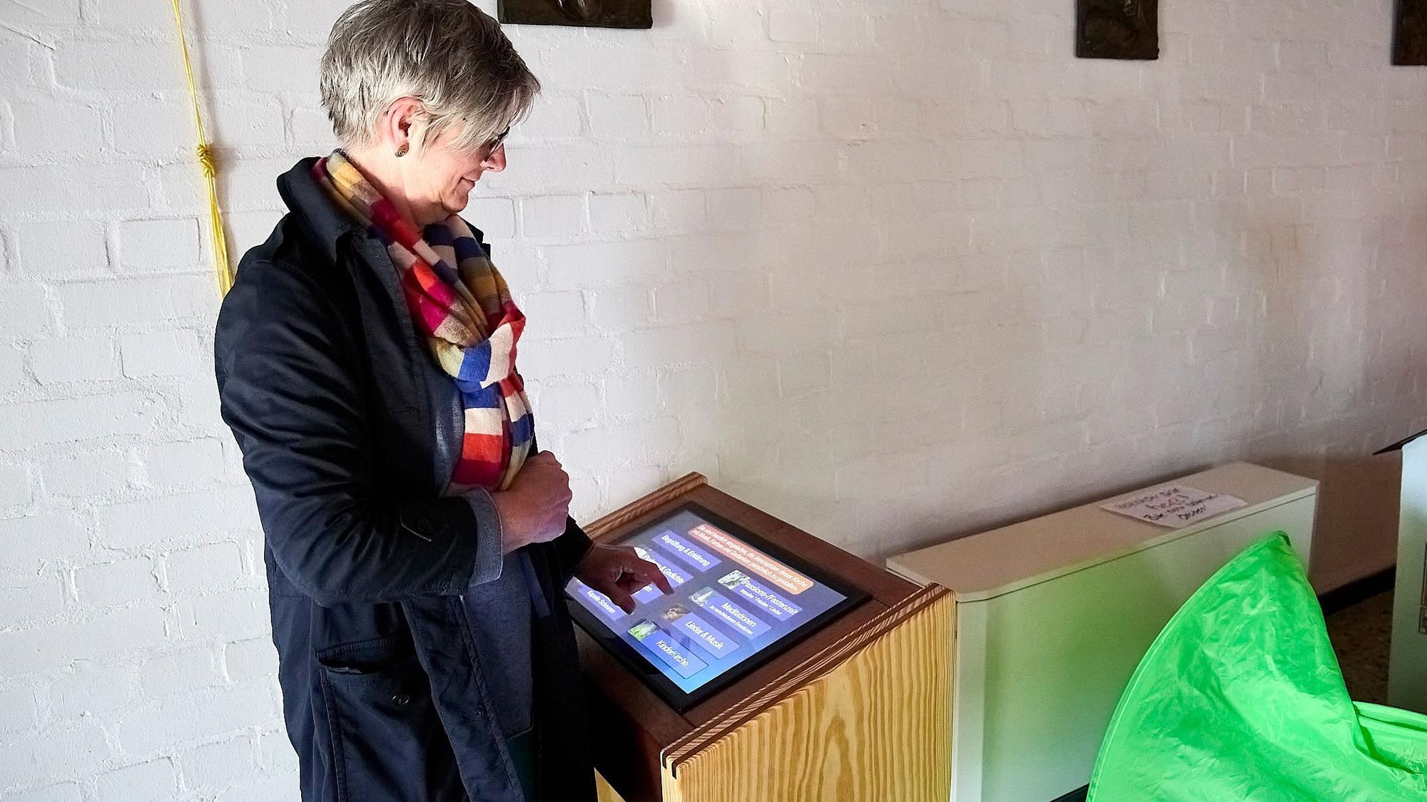 Eine Frau steht an einem Pult, in dem ein Computerbildschirm eingelassen ist.