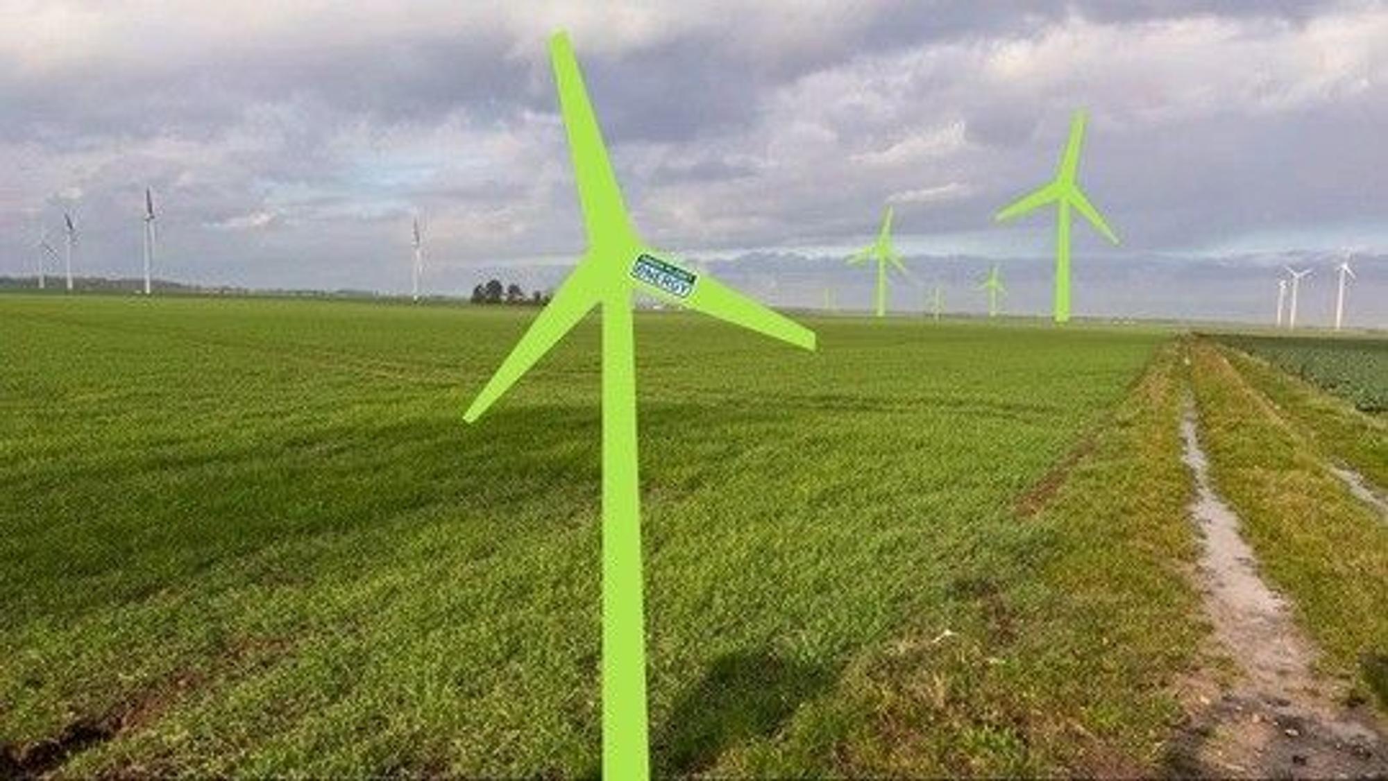 Auf einer Wiese stehen grüne Pappaufsteller in Form von Windrädern.