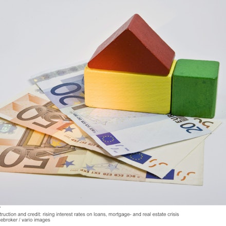 Ein Spielzeughaus aus Holz steht auf zwei 50- und einem 20-Euro-Schein. (Symbolfoto)