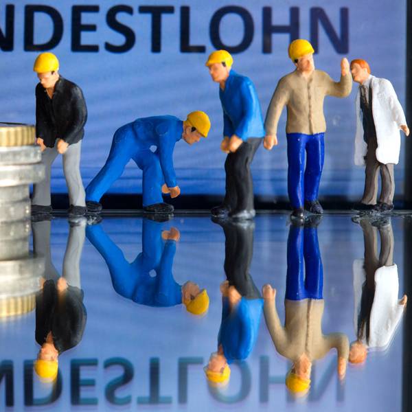 Miniaturfiguren stehen vor einem Display mit der Anzeige «Mindestlohn» (gestelltes Foto).