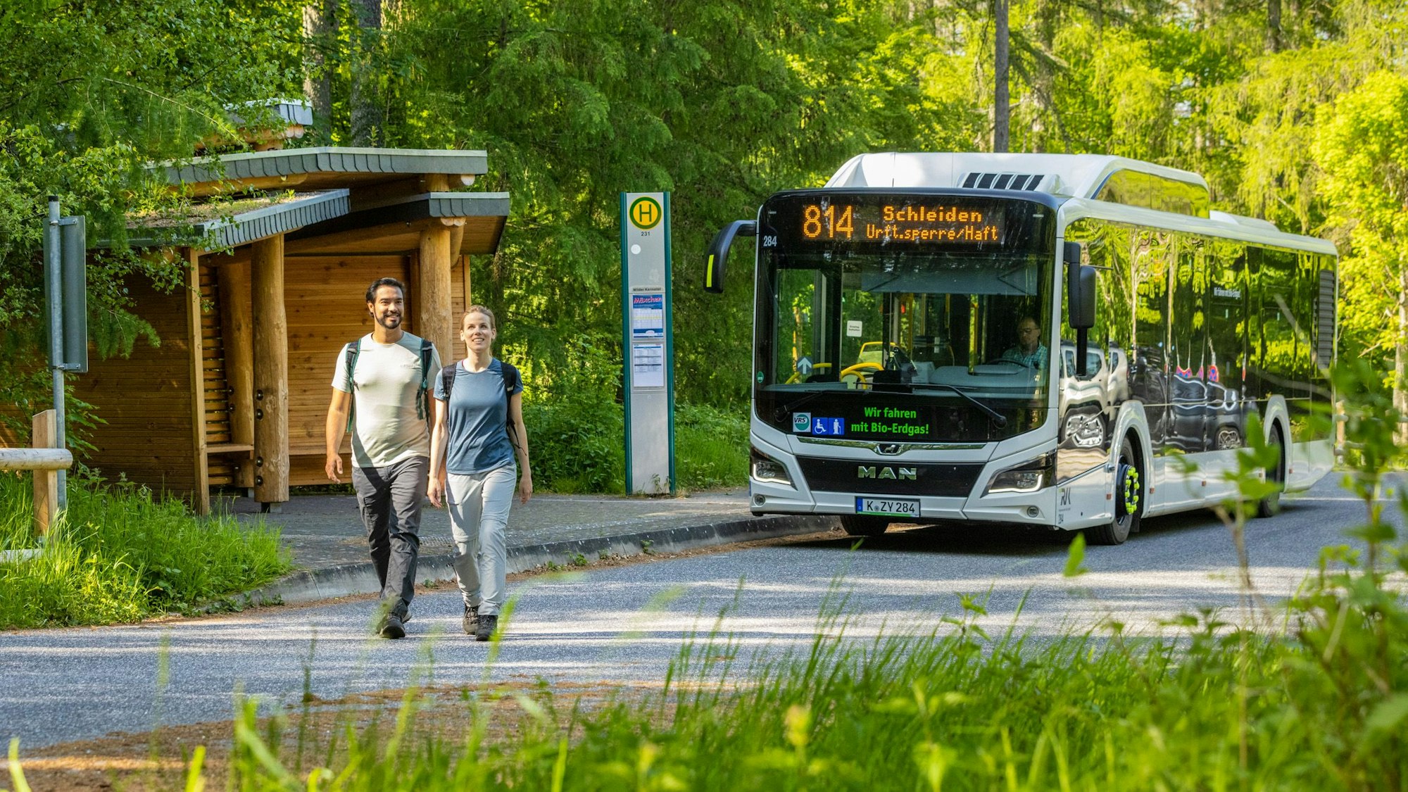 Der Eifelwanderbus der Linie 814 hat ein Wander-Pärchen an einer Bushaltestelle im Wald abgesetzt.
