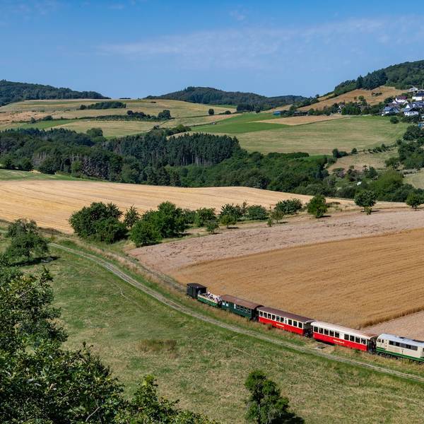 Der Vulkan-Express erschließt die Vulkanregion Laacher See - im Sommer sogar mit einem Cabriowagen. Kombinationen z.B. mit Burg Olbrück (Hintergrund) versprechen einen schönen Ausflug.