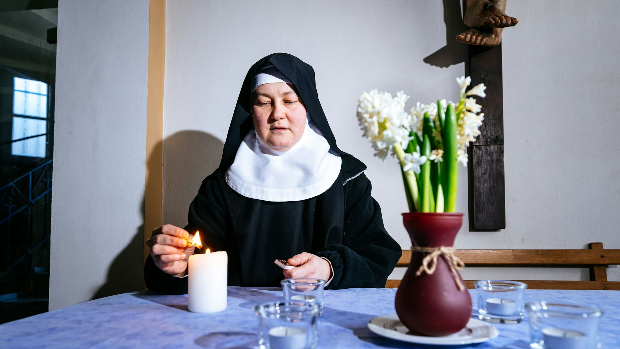 Schwester Agnes zündet eine Kerze an.