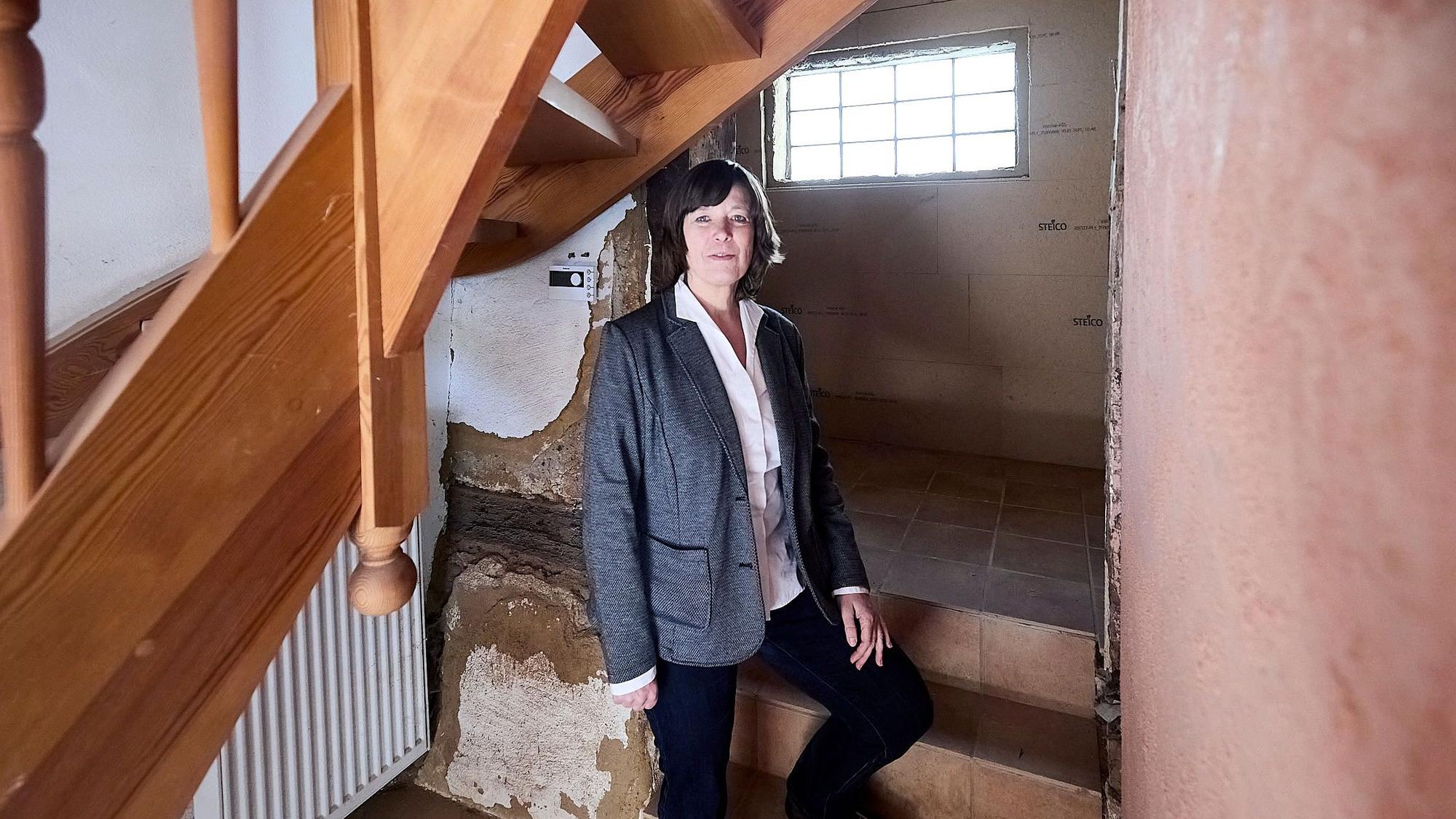 Die Frau steht in einem Haus, das Flutschäden aufweist.