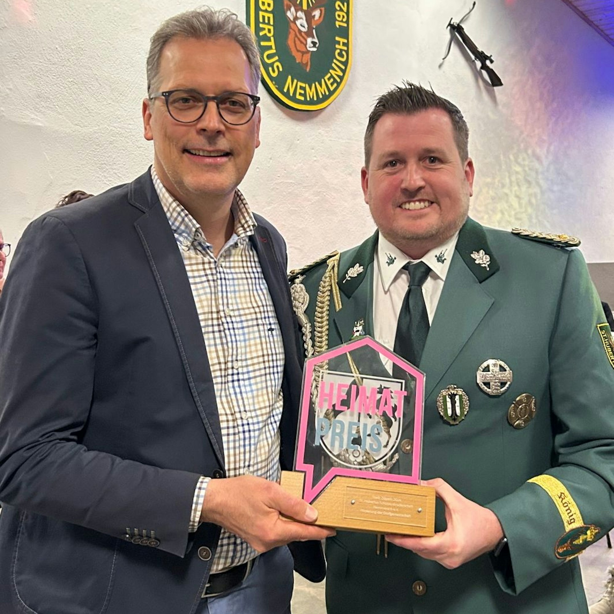 „Heimatpreis“  ist auf dem Pokal zu lesen, den Bürgermeister Ulf Hürtgen an Holger Marian überreicht.