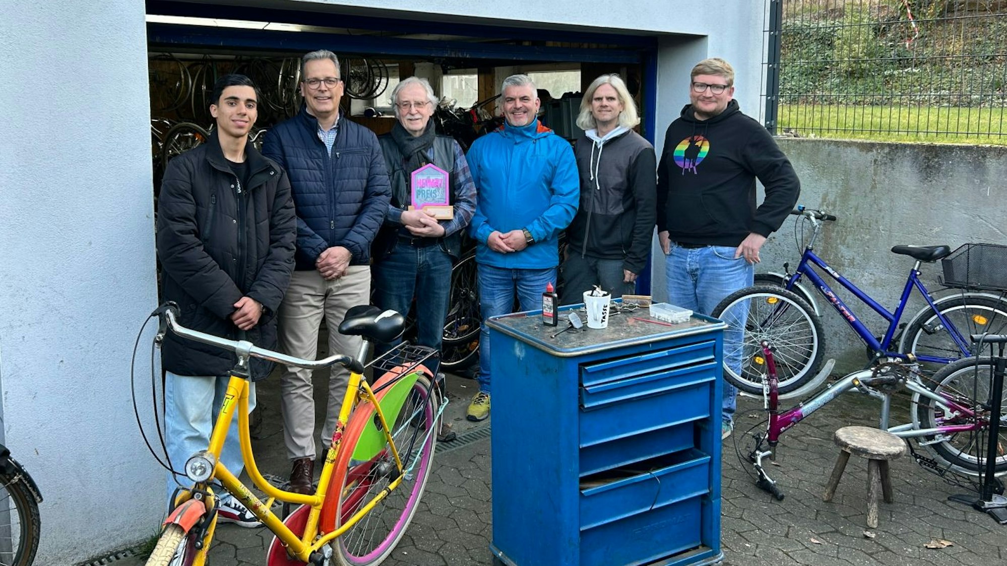 Die Sieger beim „Heimat-Preis 2024“: haben sich neben einigen Fahrrädern an ihrer Werkstatt zum Gruppenfoto aufgestellt.